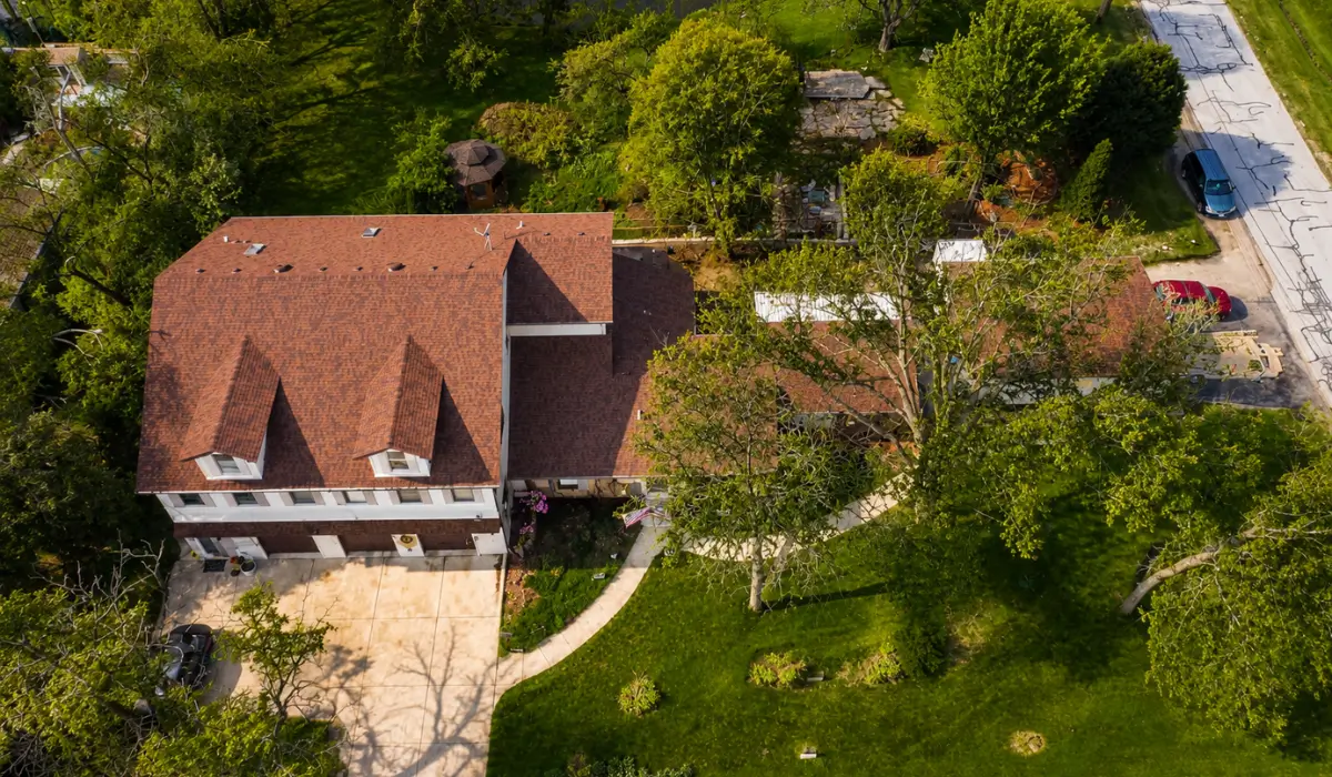 Aerial view of a residential Illinois home with a professionally installed asphalt shingle roof, showcasing how Top Roofing Materials perform during hot Illinois summers with strong sun exposure, seasonal storms, and long-term durability considerations.