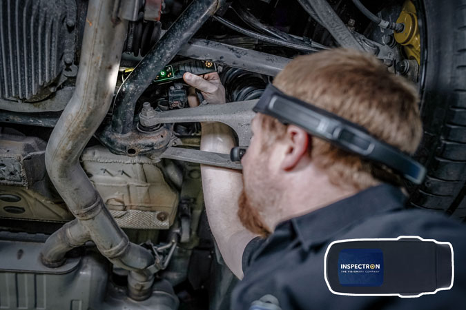 Automotive engineer inspecting a vehicle whilst wearing a RealWear Navigator headset and using an Inspectron WiTorch