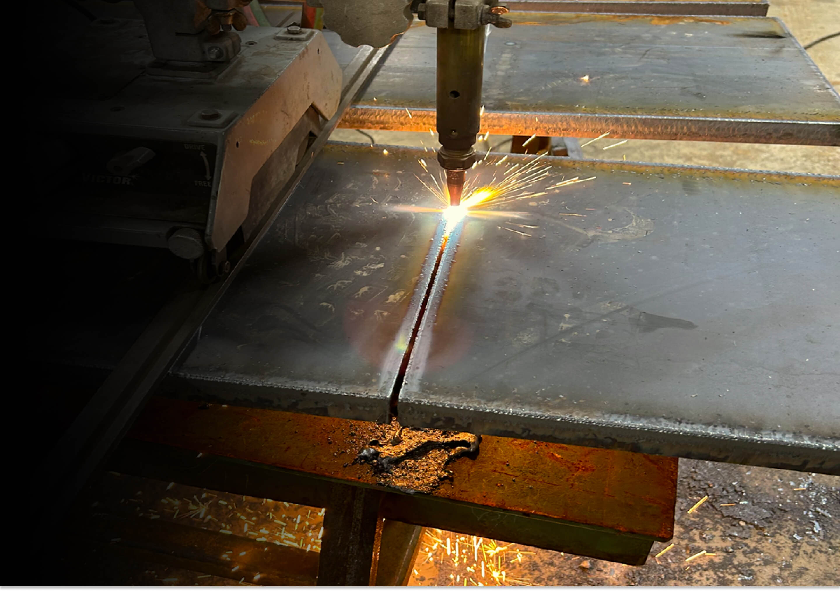 This is an image of a track torch cutting through thick metal plate.  It shows our capabilities of handling thick steel materials in our welding services and metal fabrication shop in Henderson, Texas.