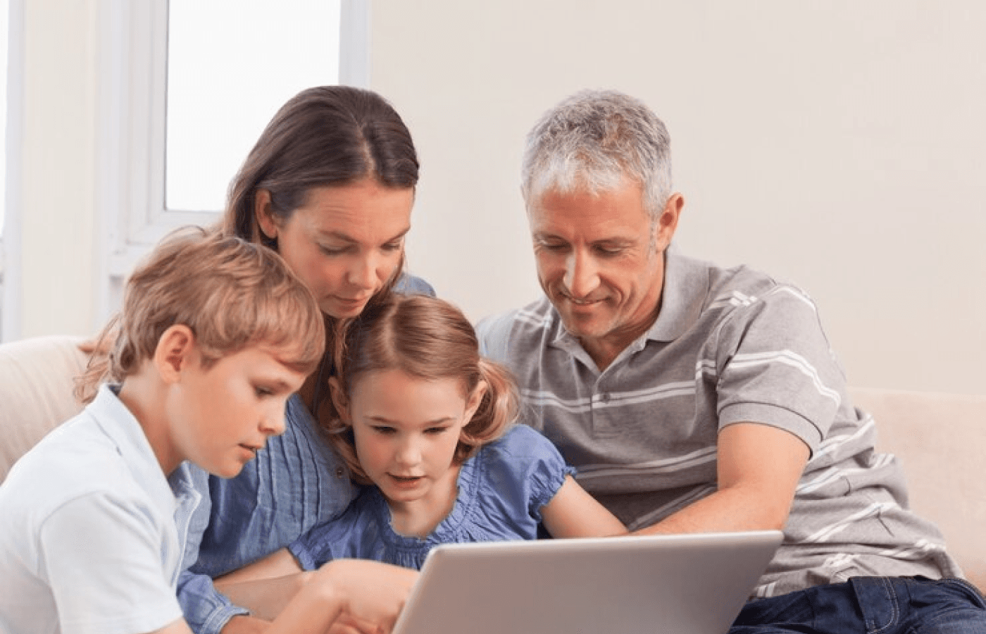 Happy family sitting on a sofa using a laptop in a living room