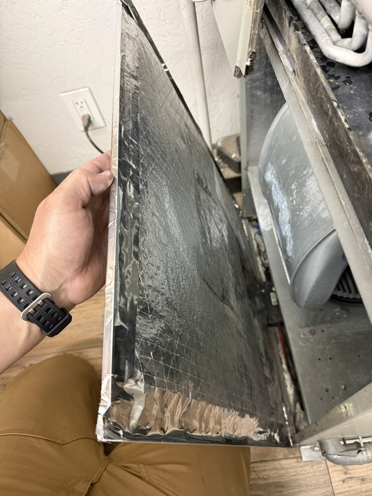 Air handler access panel re-insulated and sealed with foil tape at every seam and edge.