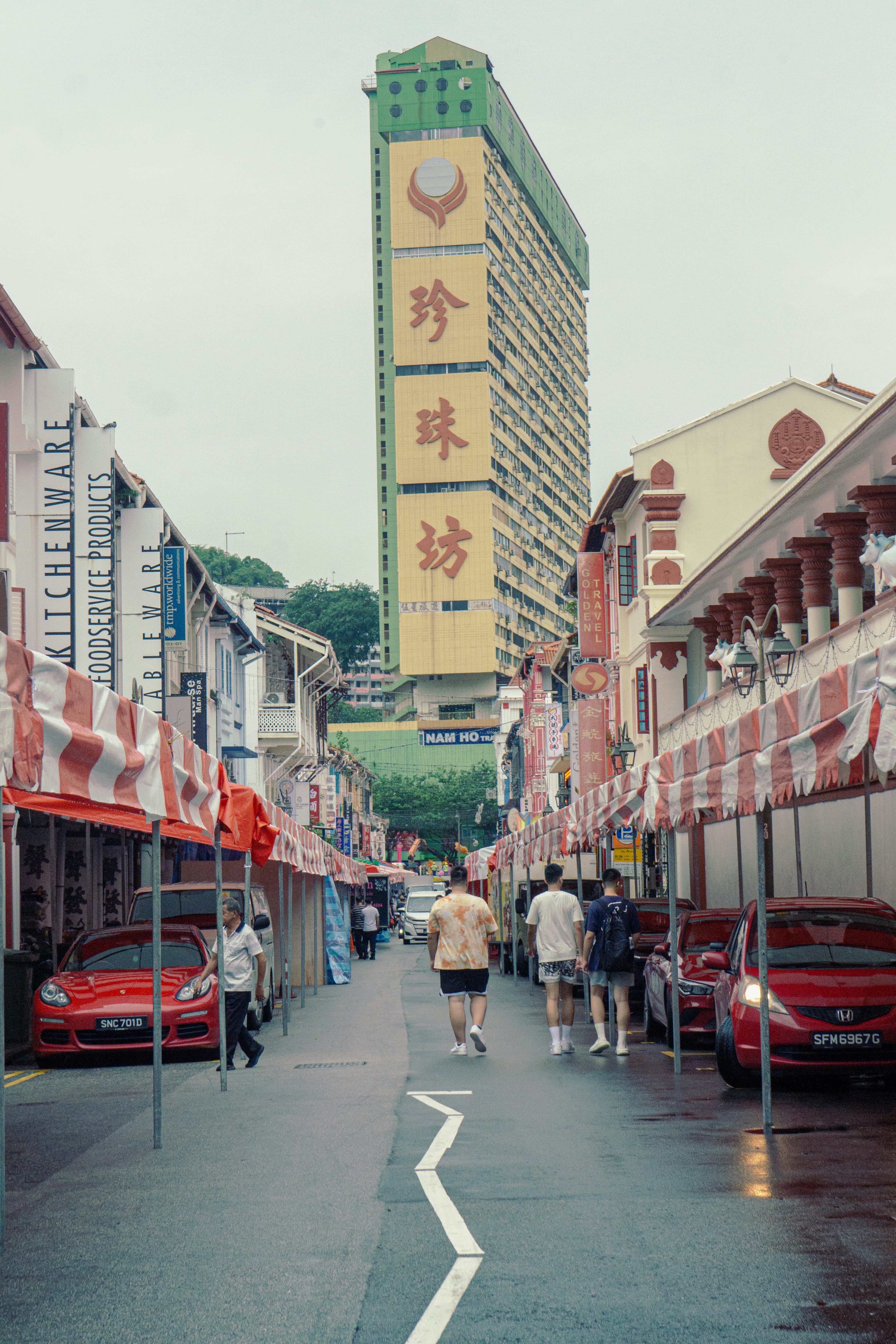 a group of people walking down a street next to tall buildings