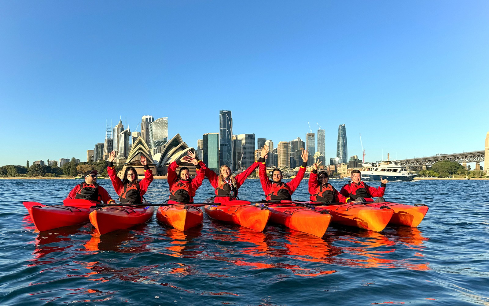 一群人正在悉尼港享受划皮艇之旅，背景是城市天際線，提供可選的早餐