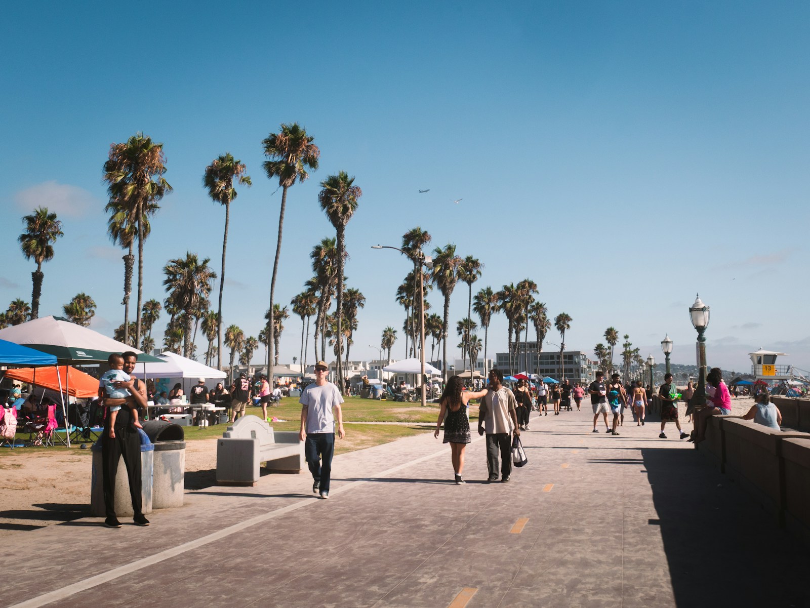 People strolling through an outdoor vendor market with palm trees