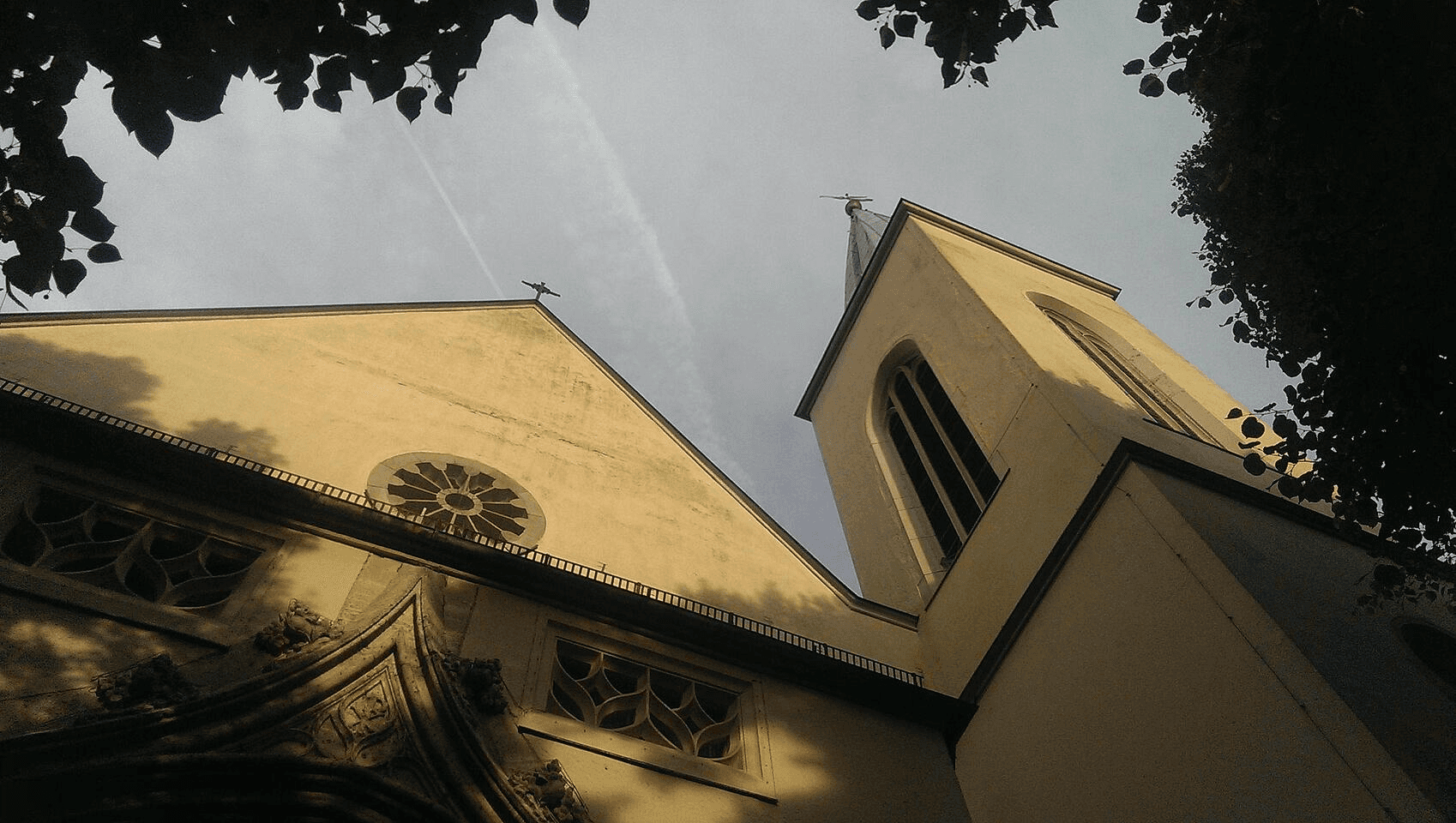 Outdoor restaurant terrace overlooking a tranquil lake at sunset. White tables and chairs are set with glassware. Sheer curtains add elegance. Calm ambiance.