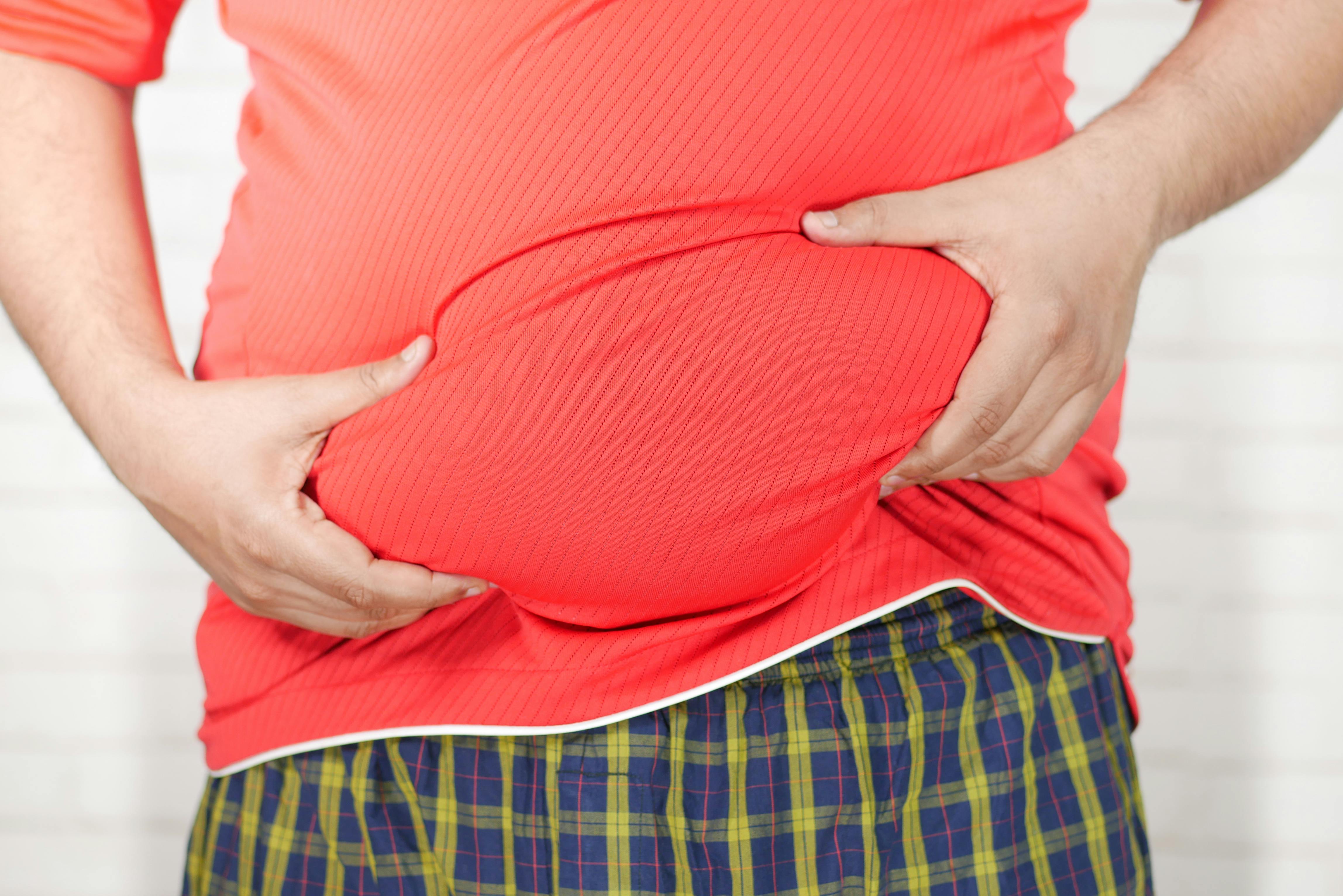 close-up-image-of-a-man-holding-his-bloated-belly-while-wearing-a-red-shirt. - towfiqu-barbhuiya (pexels)