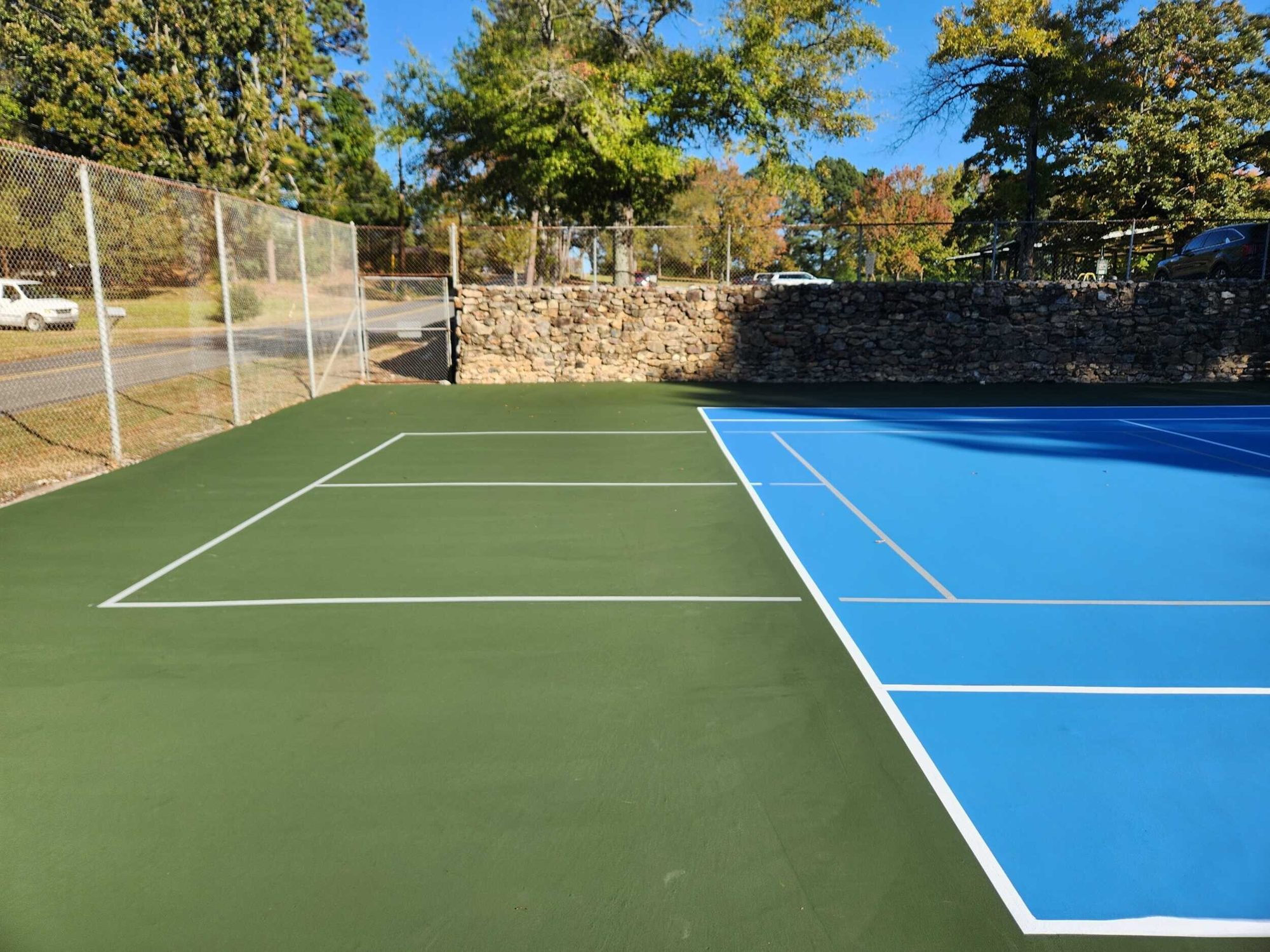 Resurfaced tennis court and green apron beside the stone wall at Family Park in Hot Springs, AR