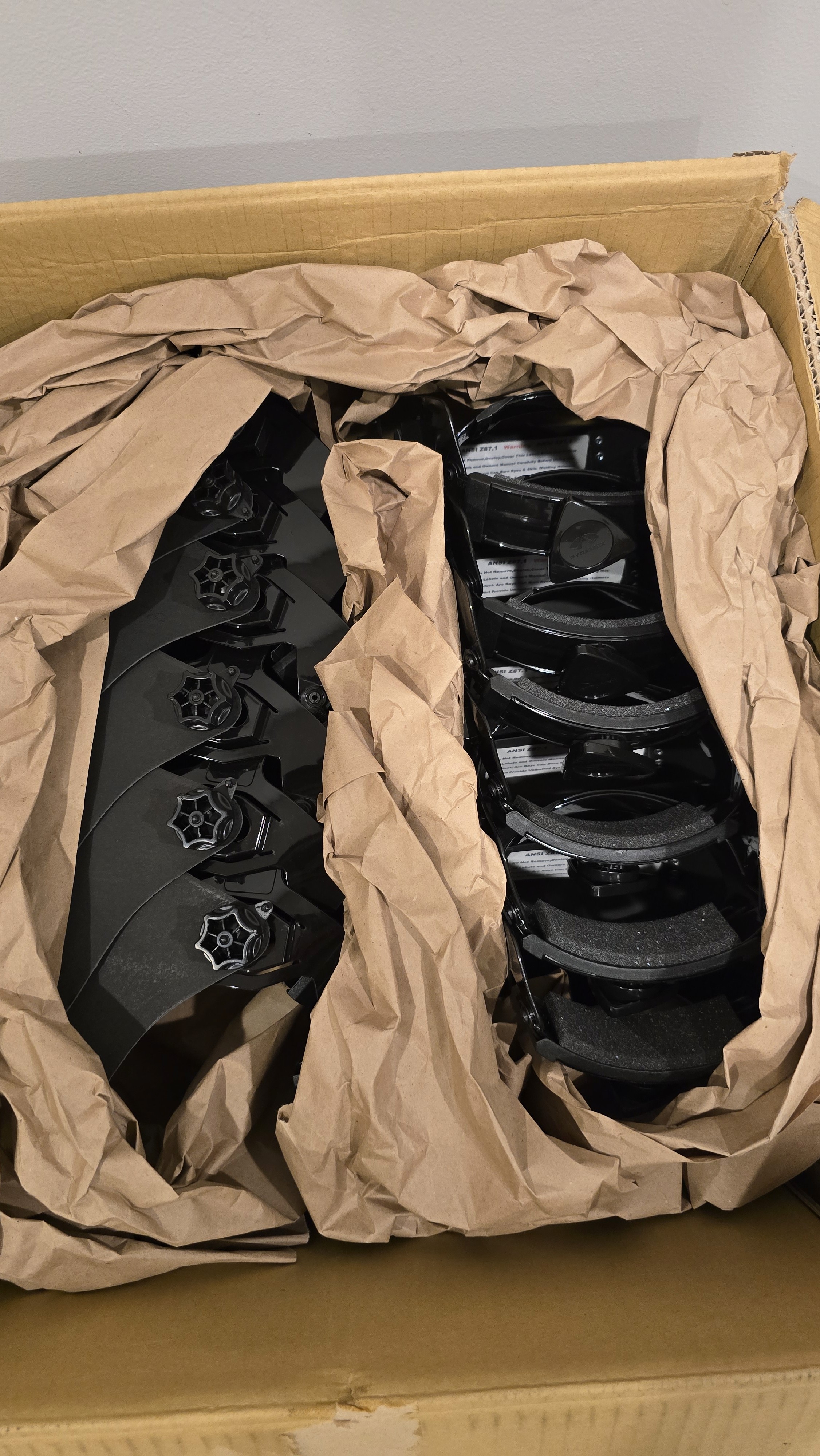 A smiling woman with her arms crossed, standing against a dark green background. She has long, dark hair.