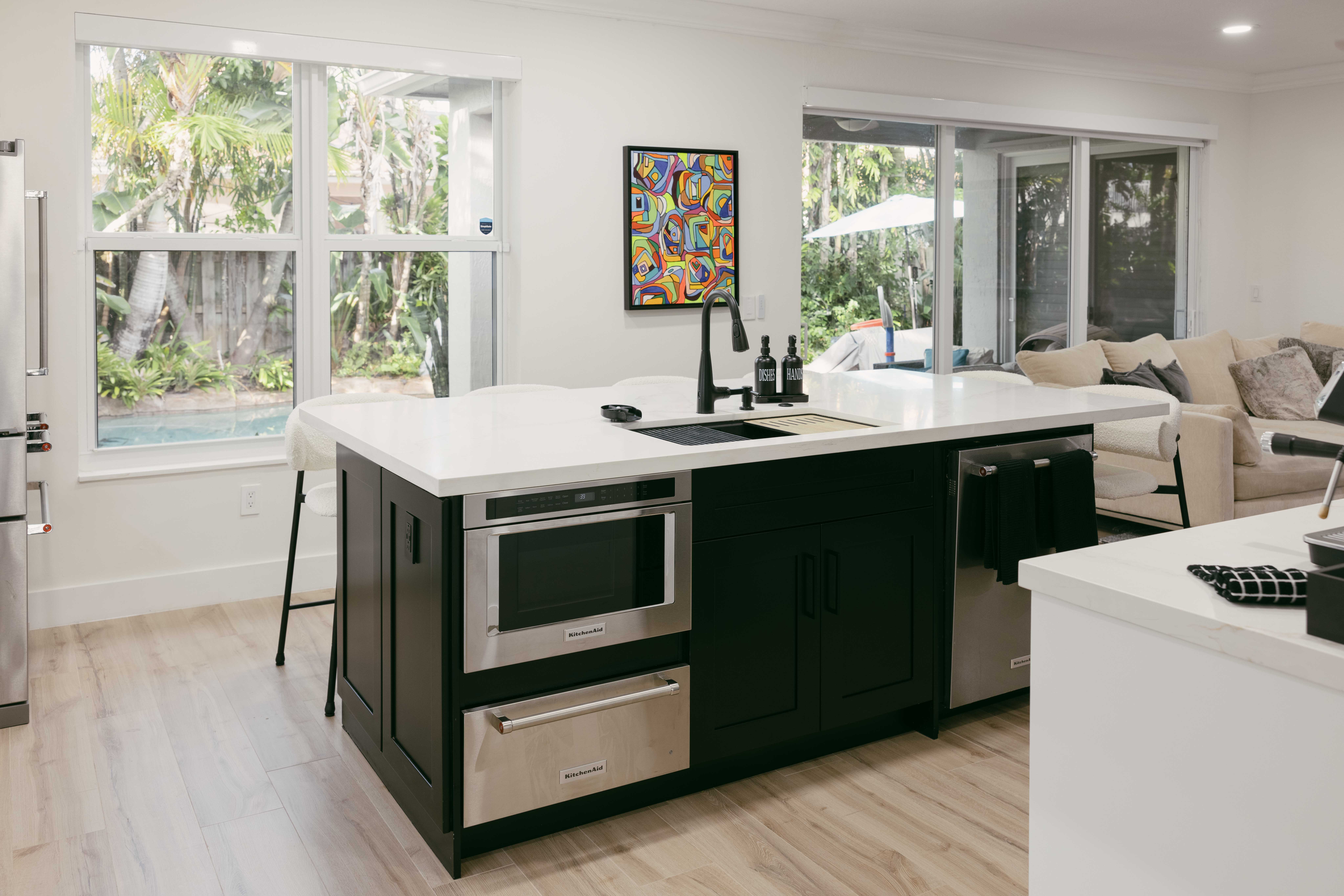 Modern kitchen island with microwave, dishwasher, sink, and island seating.