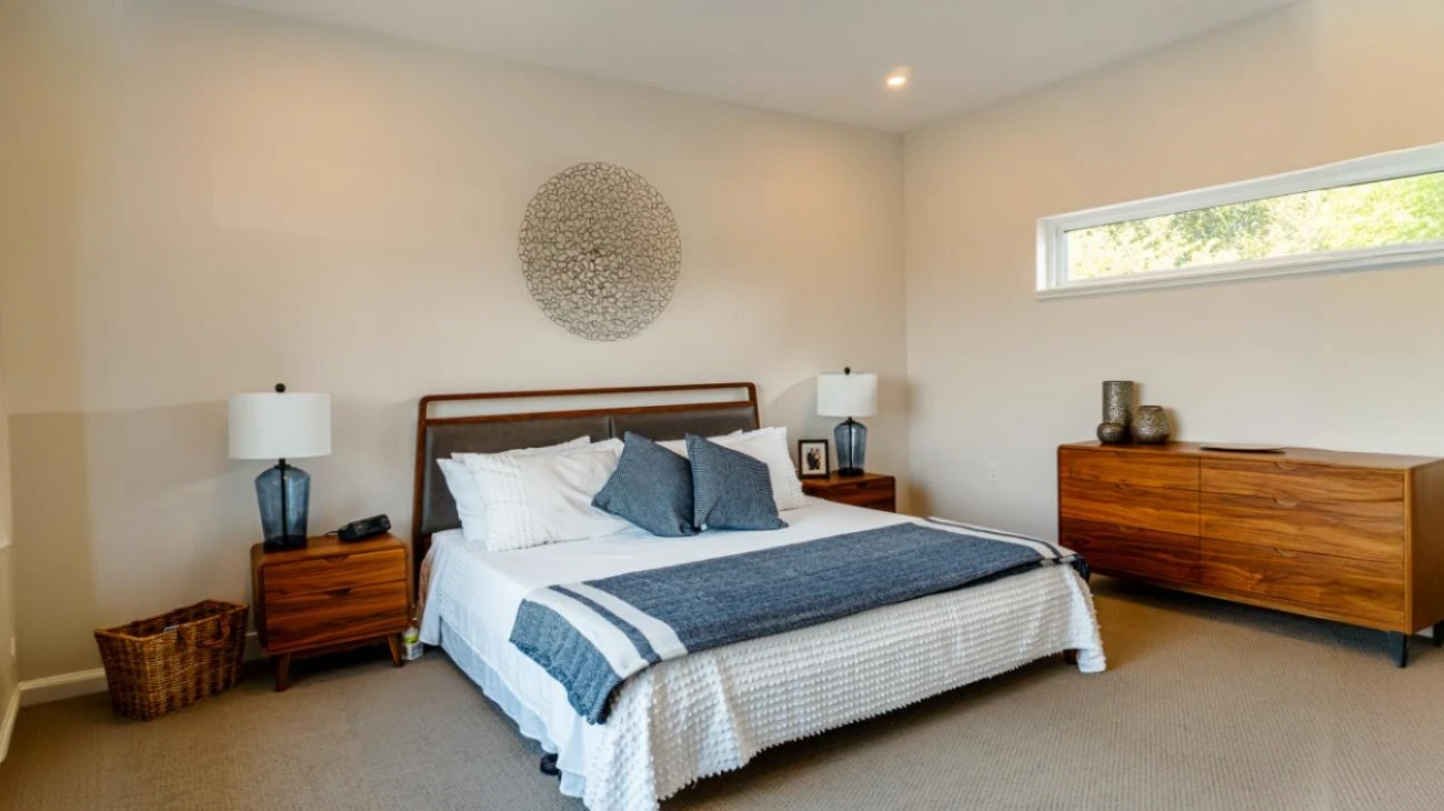 Spacious master bedroom with king-size bed, designer nightstands, and circular metal wall art in Burnaby custom home