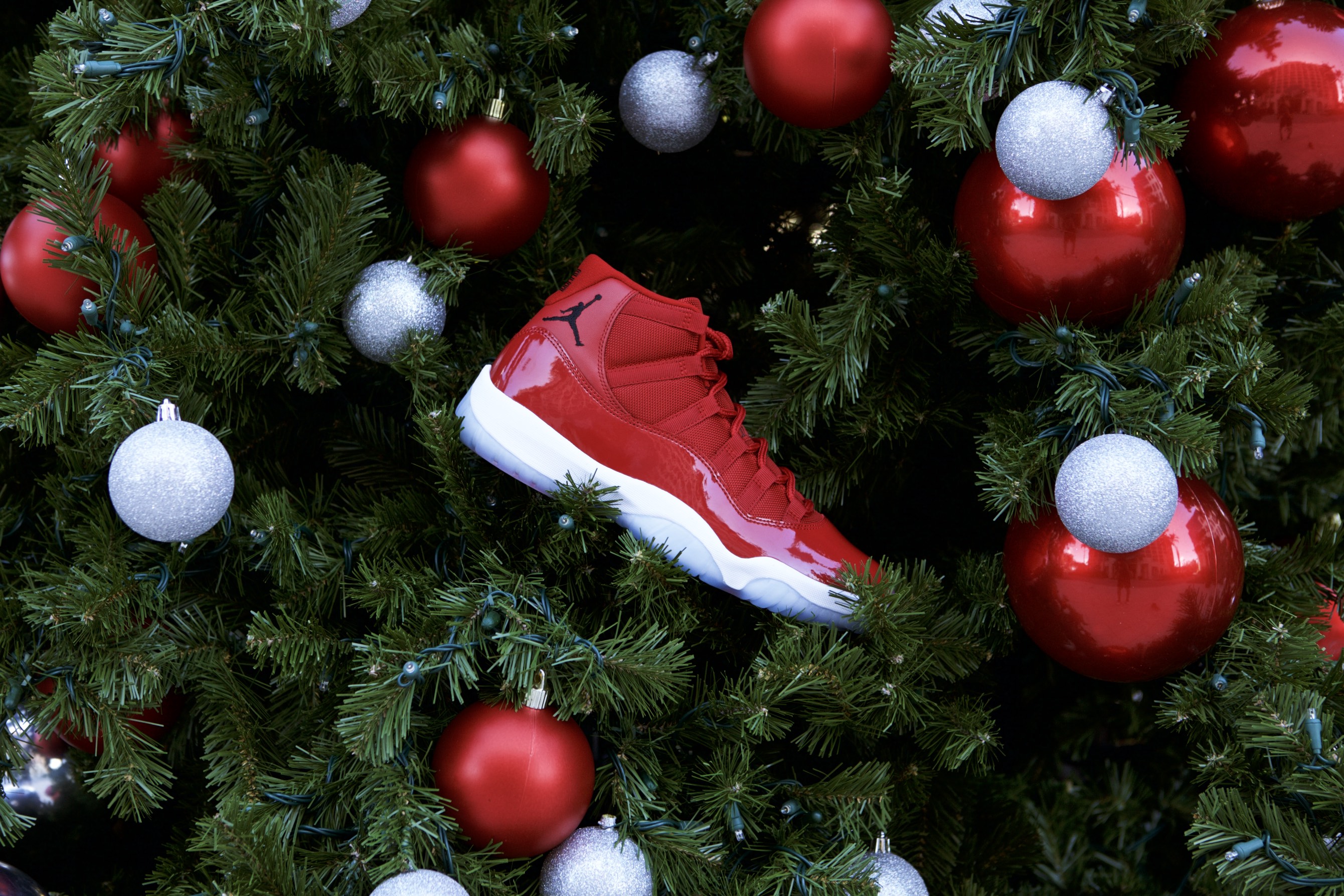 Red sneaker placed in a Christmas tree among red and silver ornaments.