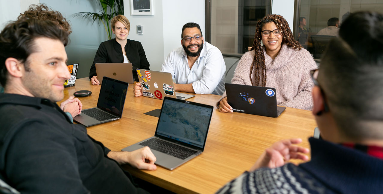 Two designers sketching homepage wireframes and layout ideas on a whiteboard with sticky notes