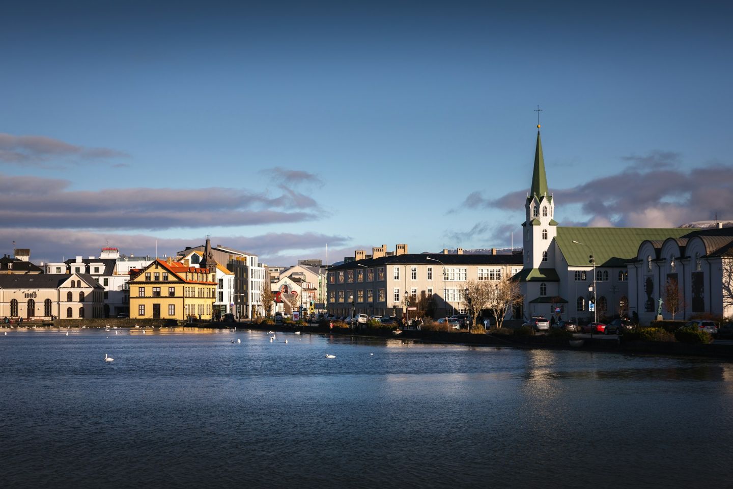 View of Tjörnin Lake and Fríkirkjan church in downtown Reykjavík on a clear day.