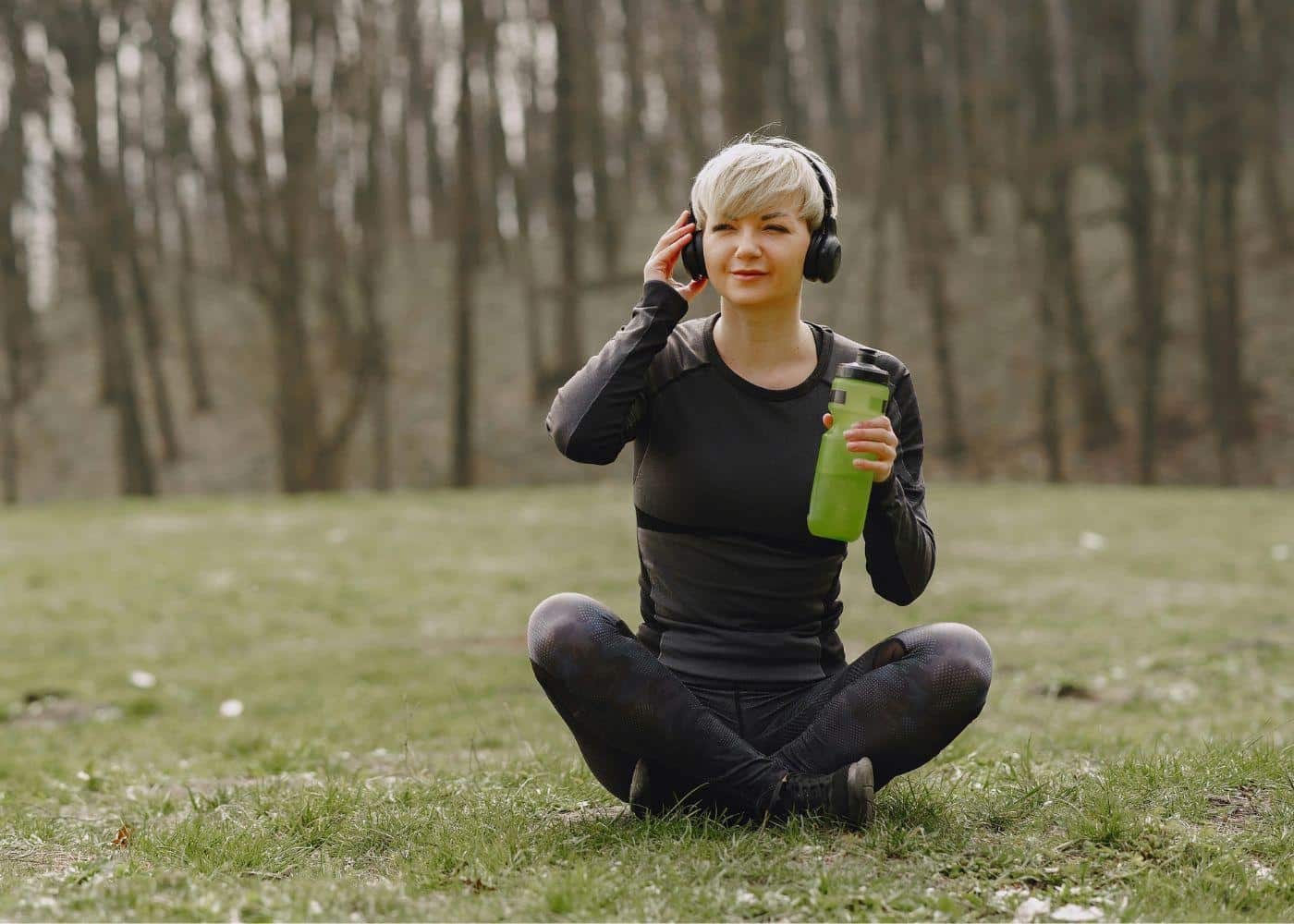 Headspace Vs Waking Up: Woman meditating on the grass with headphones on