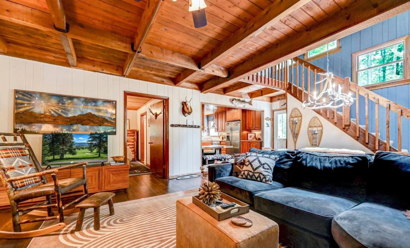 Living room with dark sectional, rocking chair and landscape art at Mountain MAMA