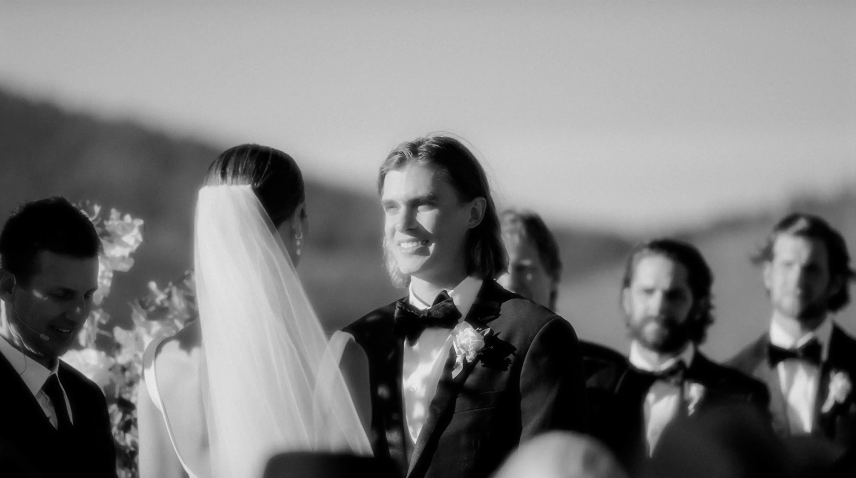 Close-up portrait of Emma and James smiling on their wedding day, groom in black tuxedo and bow tie