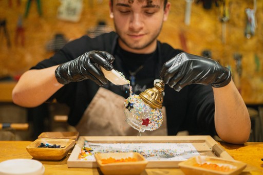 A man carefully applying colorful mosaic pieces onto a lamp during a mosaic lamp workshop in Istanbul, showcasing the detailed craftsmanship involved in creating a traditional Turkish lamp.