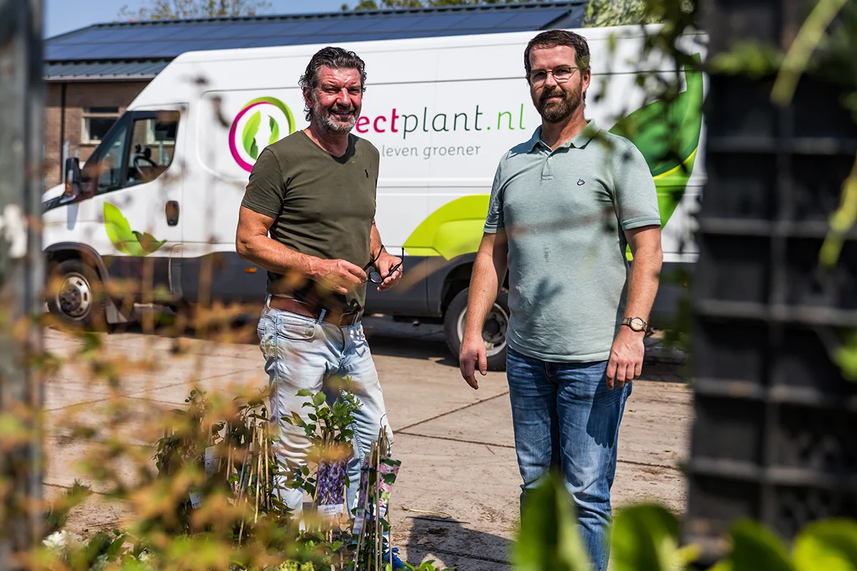 Twee medewerkers van Directplant.nl voor een bedrijfsbus tussen de planten
