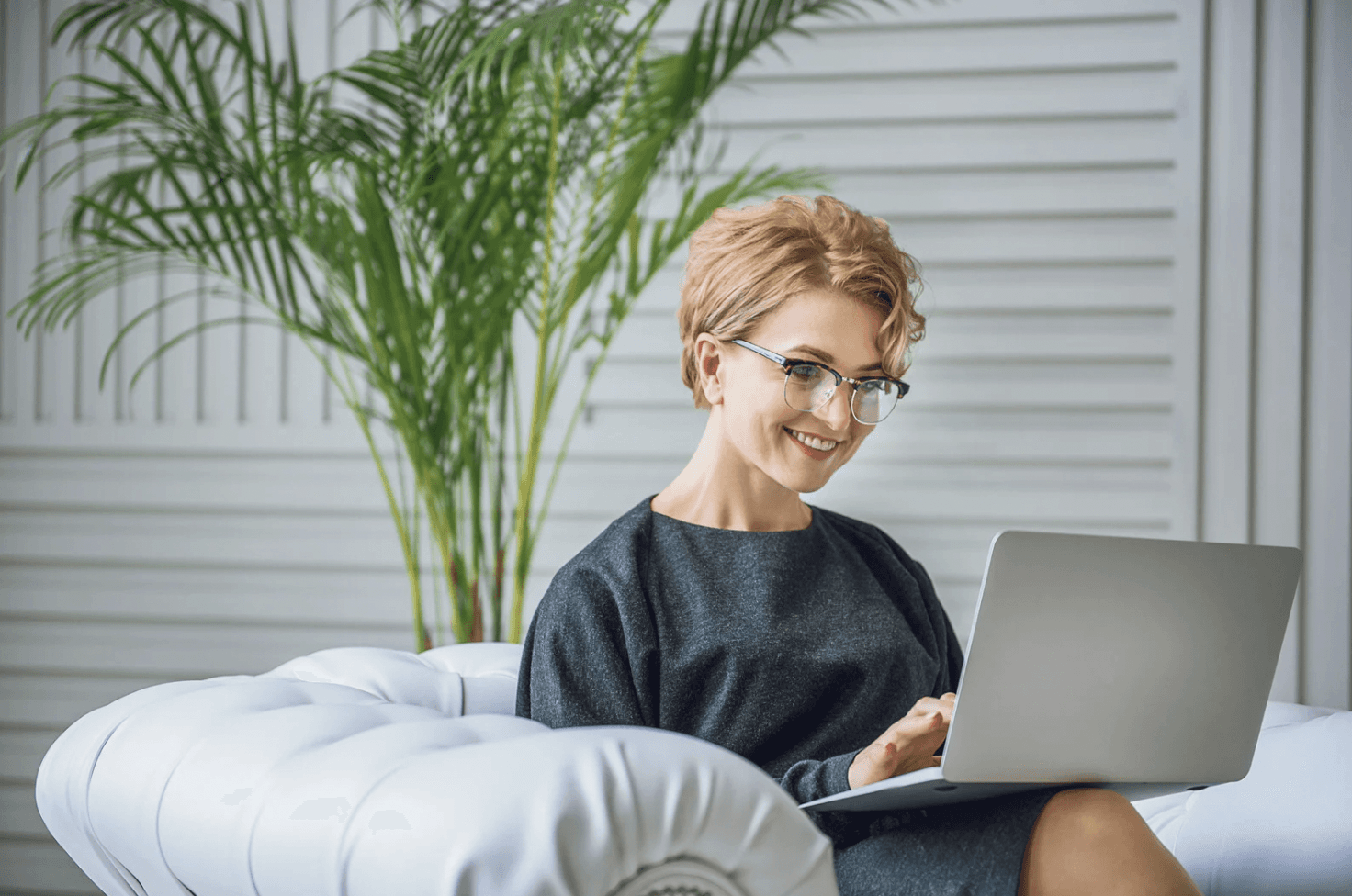 Woman smiling while working on a laptop in a bright room, representing sellers preparing Amazon FBA automation before Q4 sales surges.