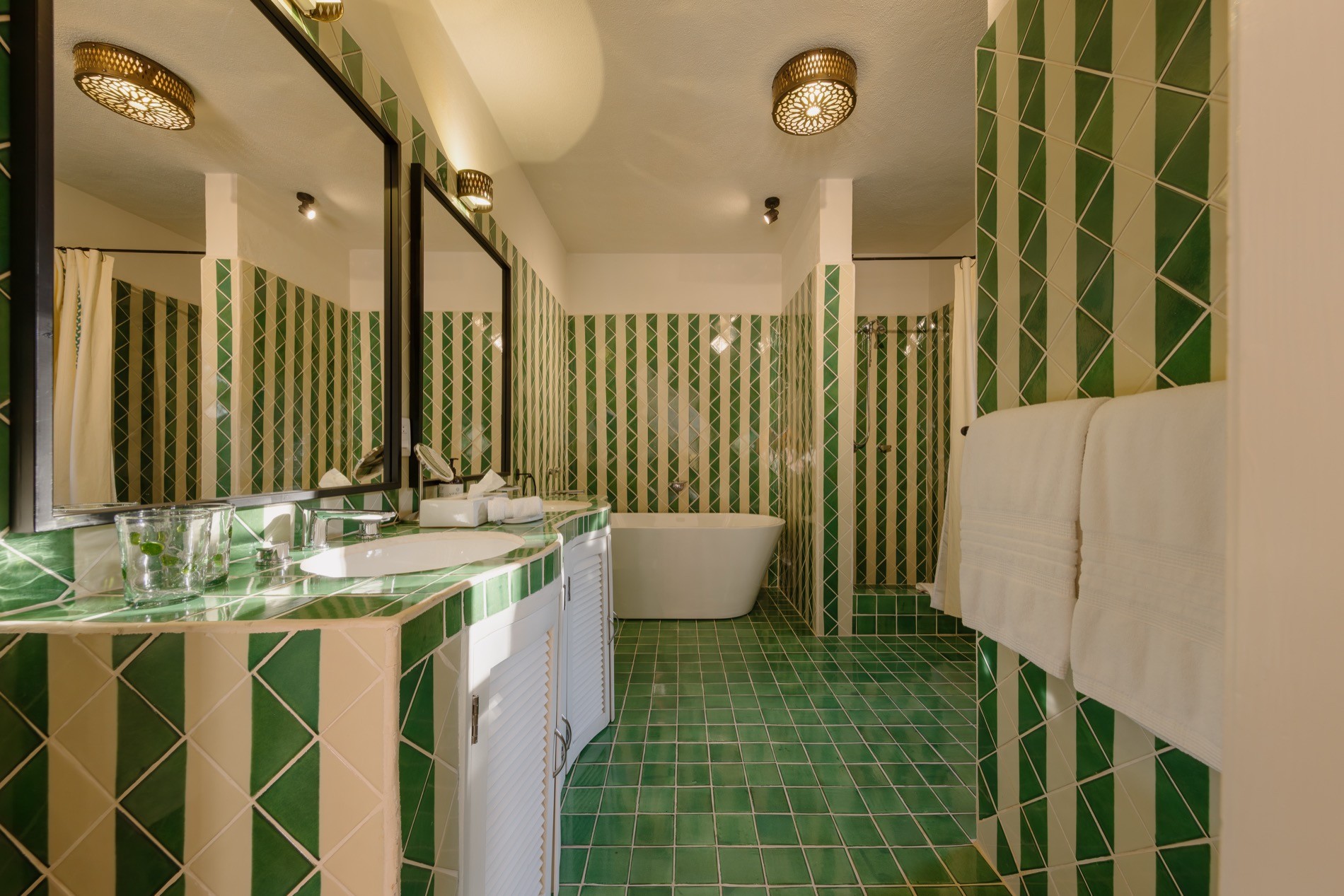 La Residencia bathroom with green geometric tile, freestanding tub, and walk-in shower