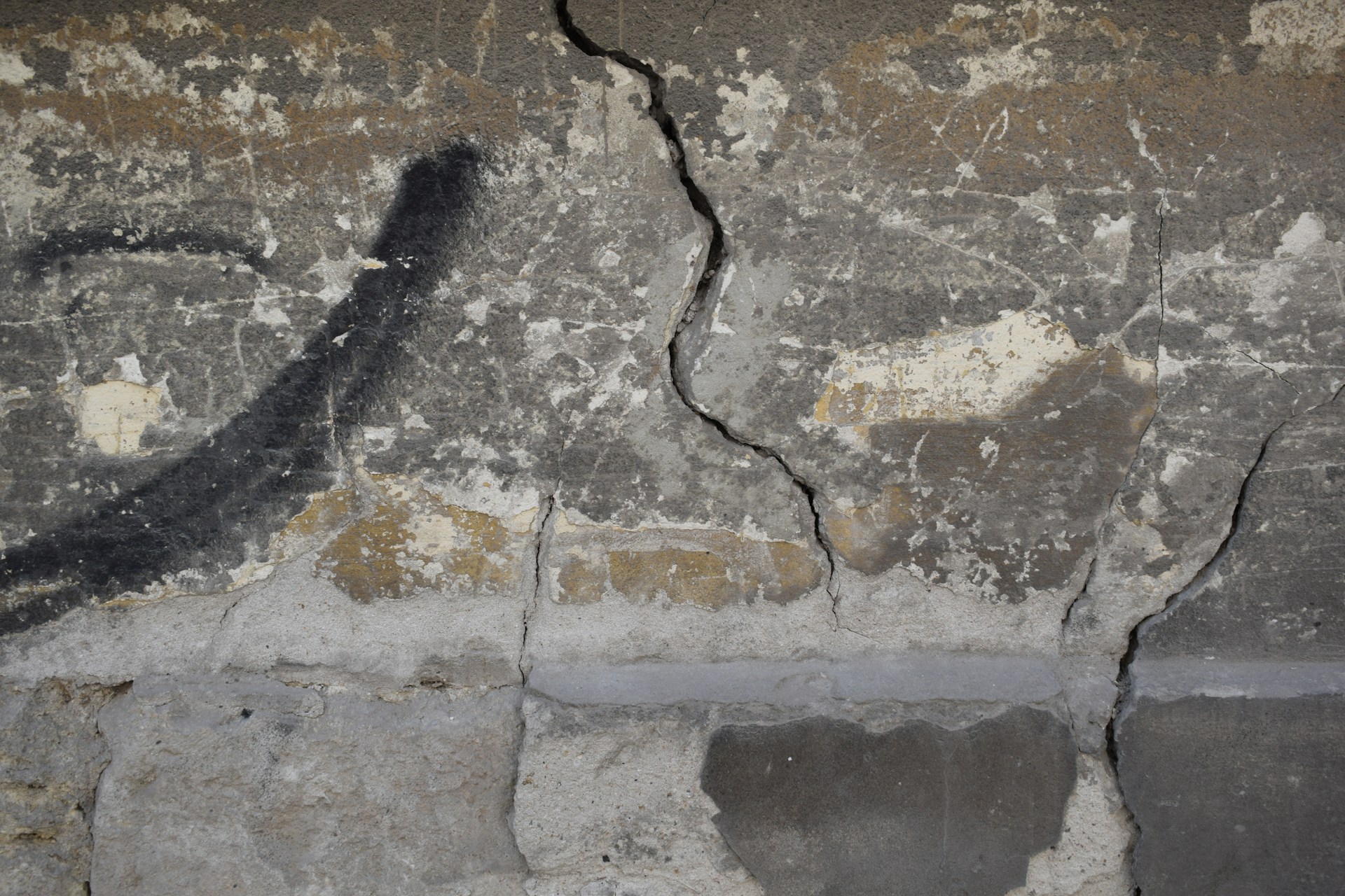 Mur de fondation en béton fissuré, montrant des signes de dégradation structurelle.