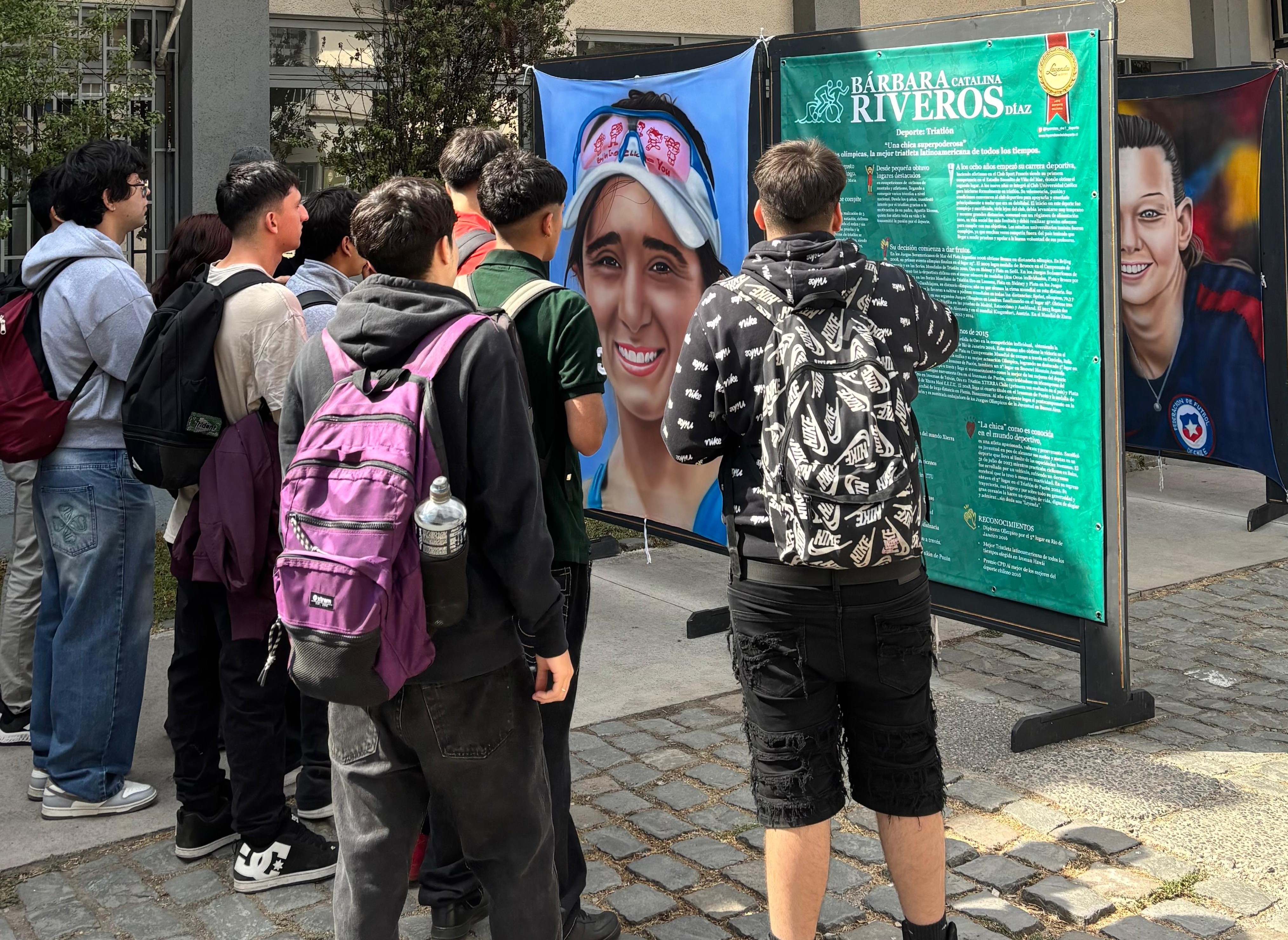 Visitantes en la exposición Leyendas del Deporte admirando la pintura de Bárbara Riveros, triatleta chilena.