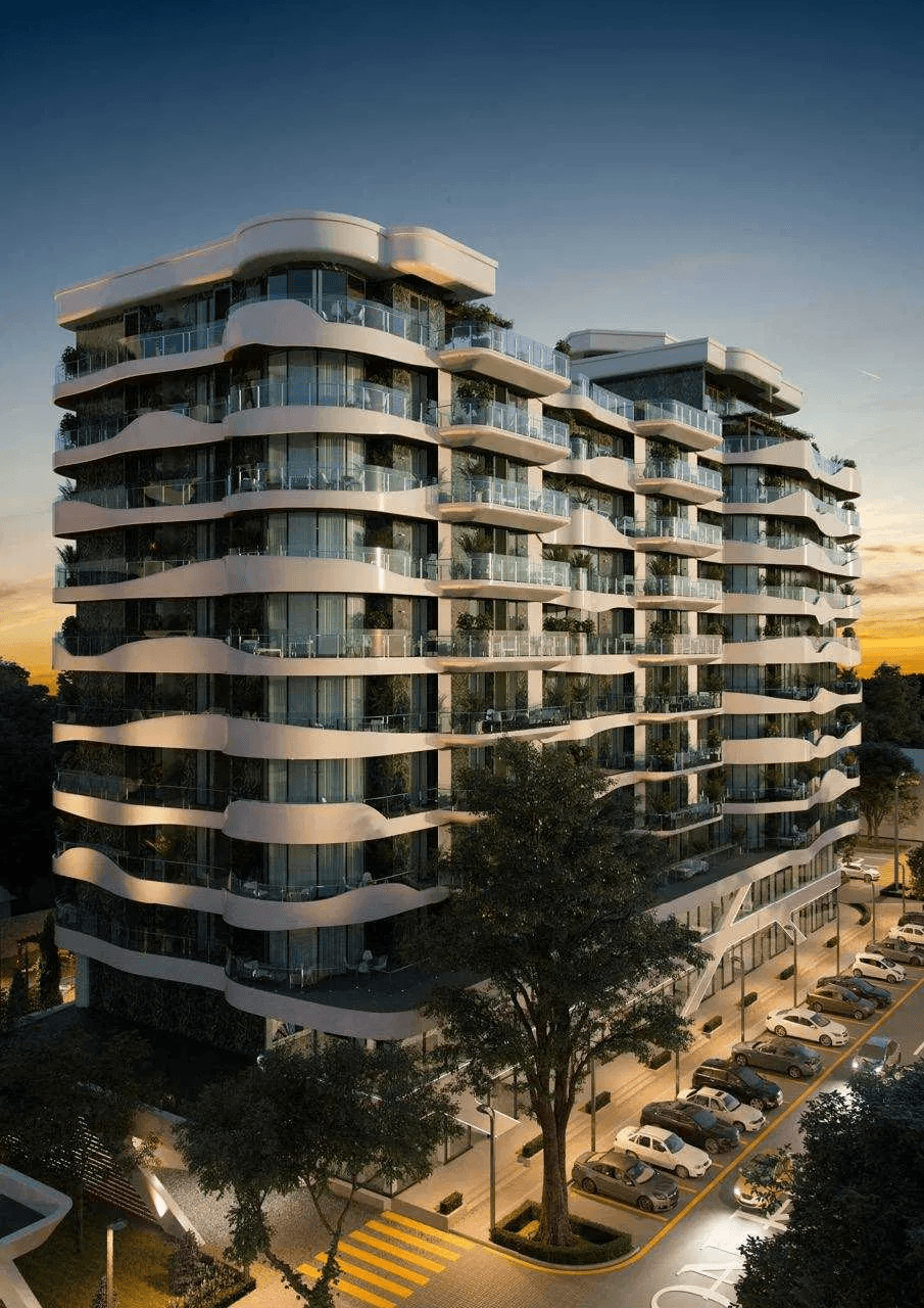 A smiling young man with crossed arms, wearing a plaid shirt and white t-shirt, poses against a dark background.