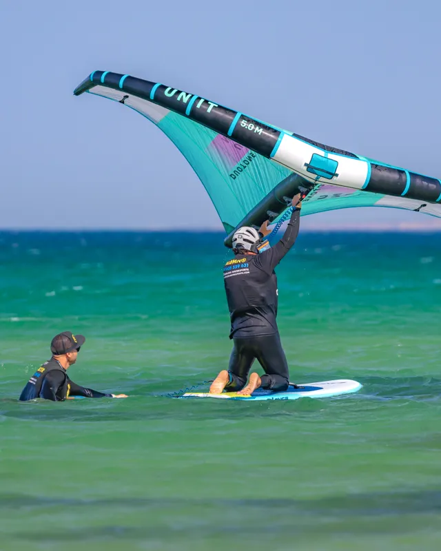 Student learning to balance on wing foil board in the water with Explora Watersports Tarifa instructor