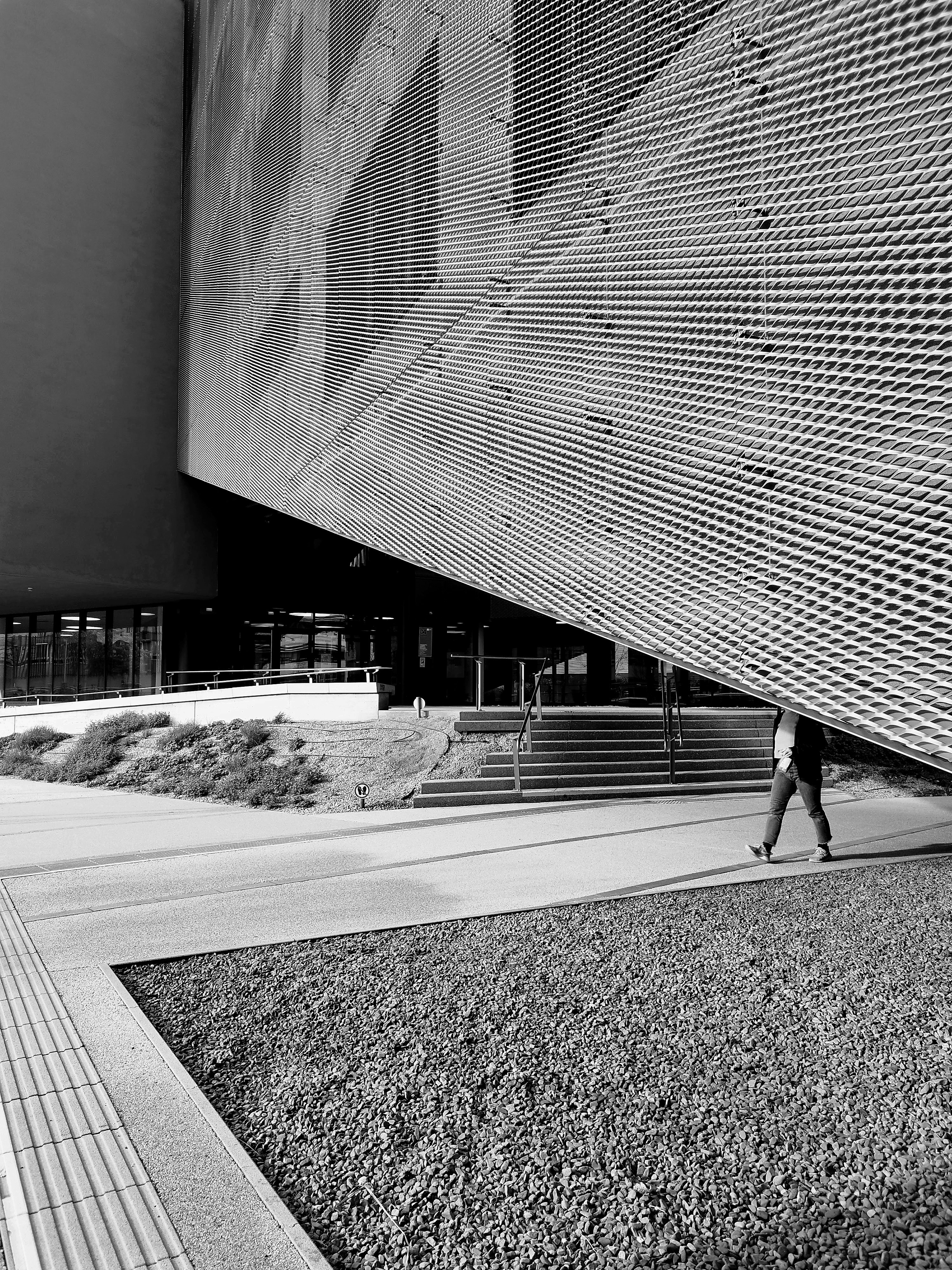 Person walks under a large modern building overhang.