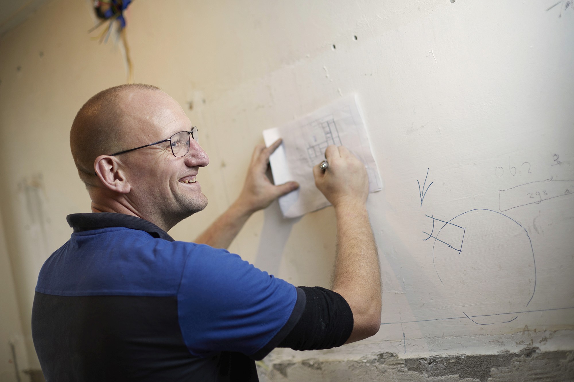 Een kind zit op een bank en aait zachtjes een zwarte hond in een met zonlicht gevulde kamer.