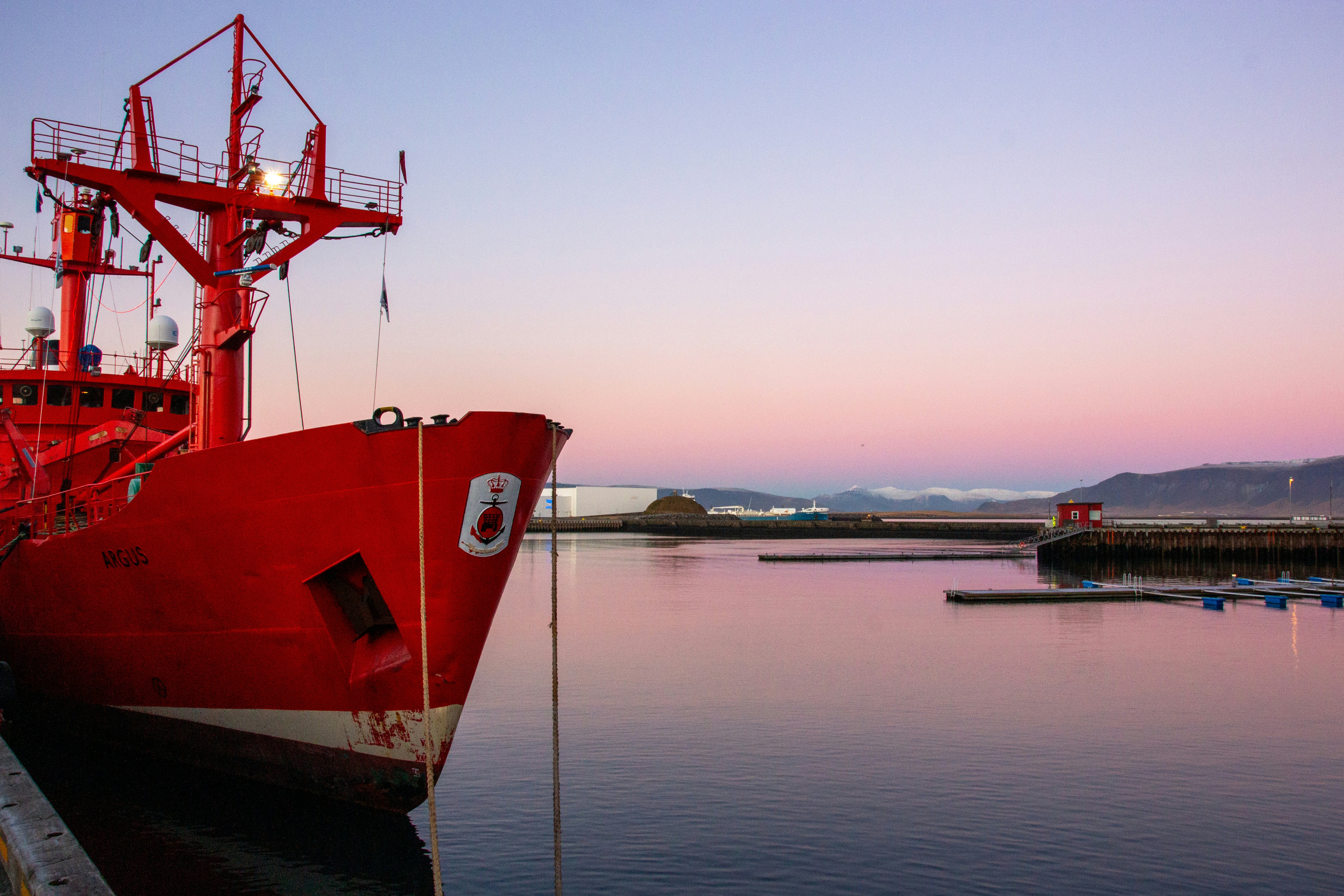 A large red boat moored in a harbor in Iceland.