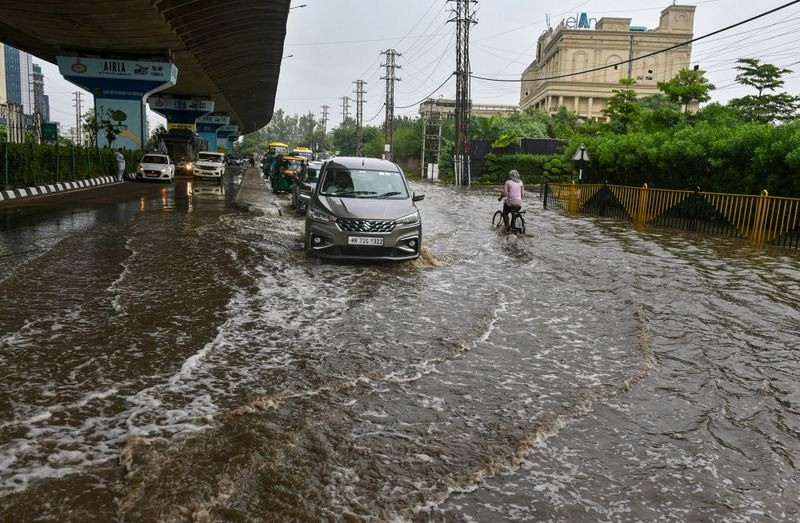 Vehicles wade through a waterlogged road at Badshahpur, Gurugram, July 8, 2026.