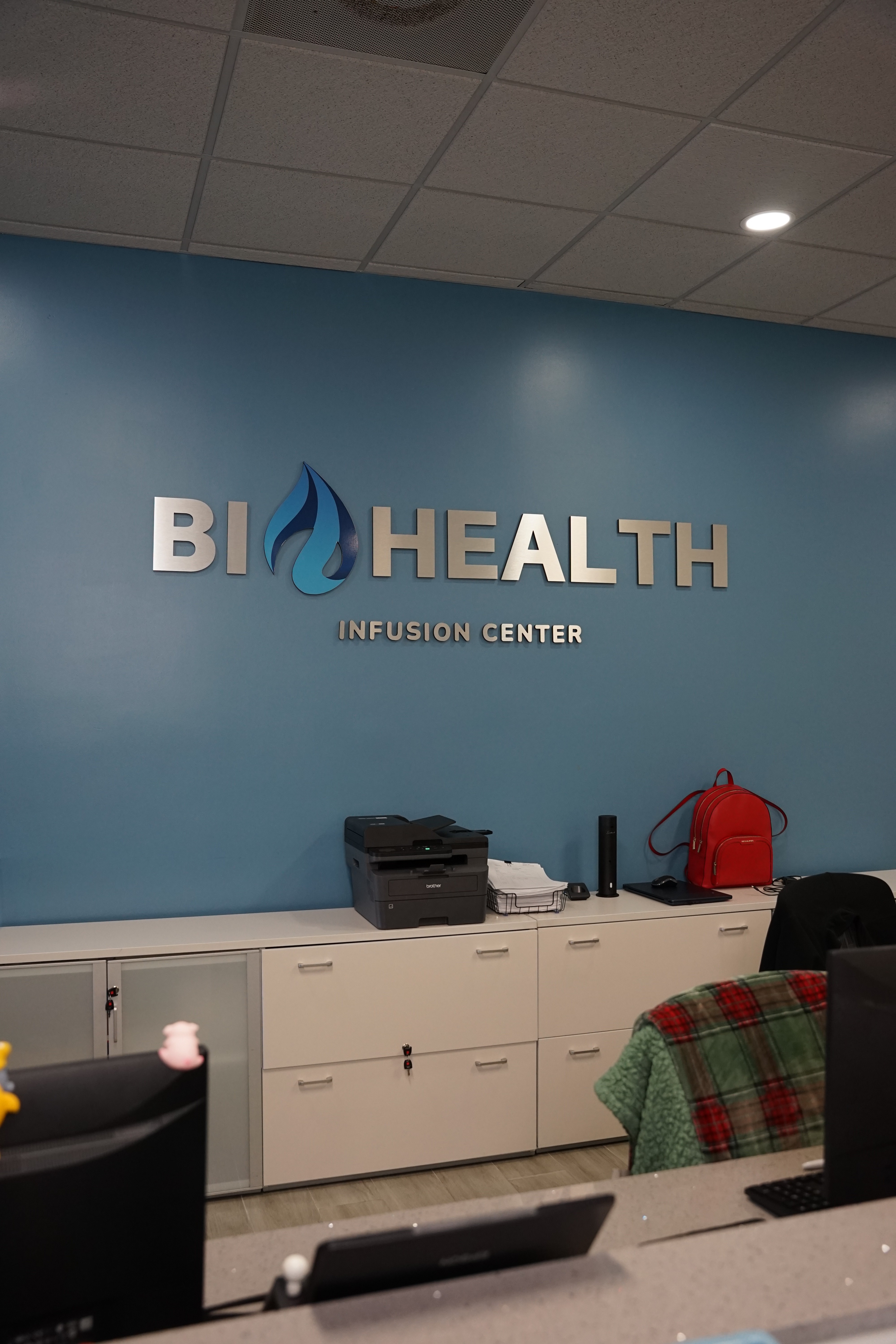 A woman stands in an office, with social media icons emerging from her laptop, symbolizing digital connectivity and engagement.