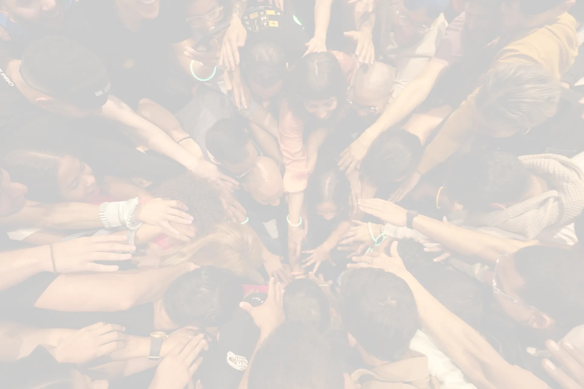 A person with long hair stands against a bright, hazy background, reaching out with one hand.