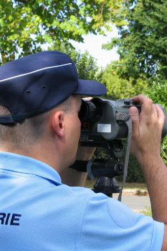 gendarme aux jumelles controllant la vitesse d'automobilistes