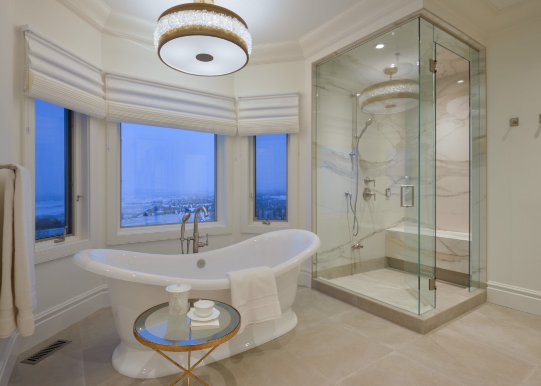 Image of Luxurious primary ensuite bathroom with freestanding tub, glass shower enclosure, and marble design by KHD Homes.
