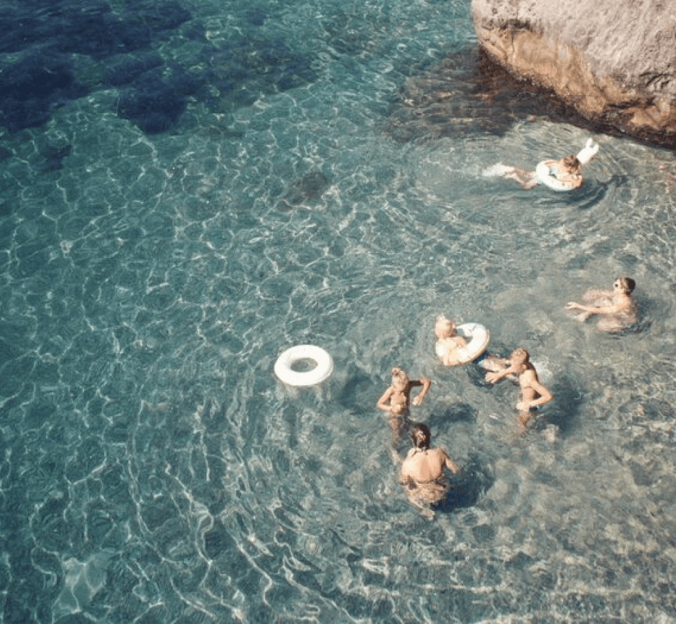 People lounging in the sea by the beach with inner tubes