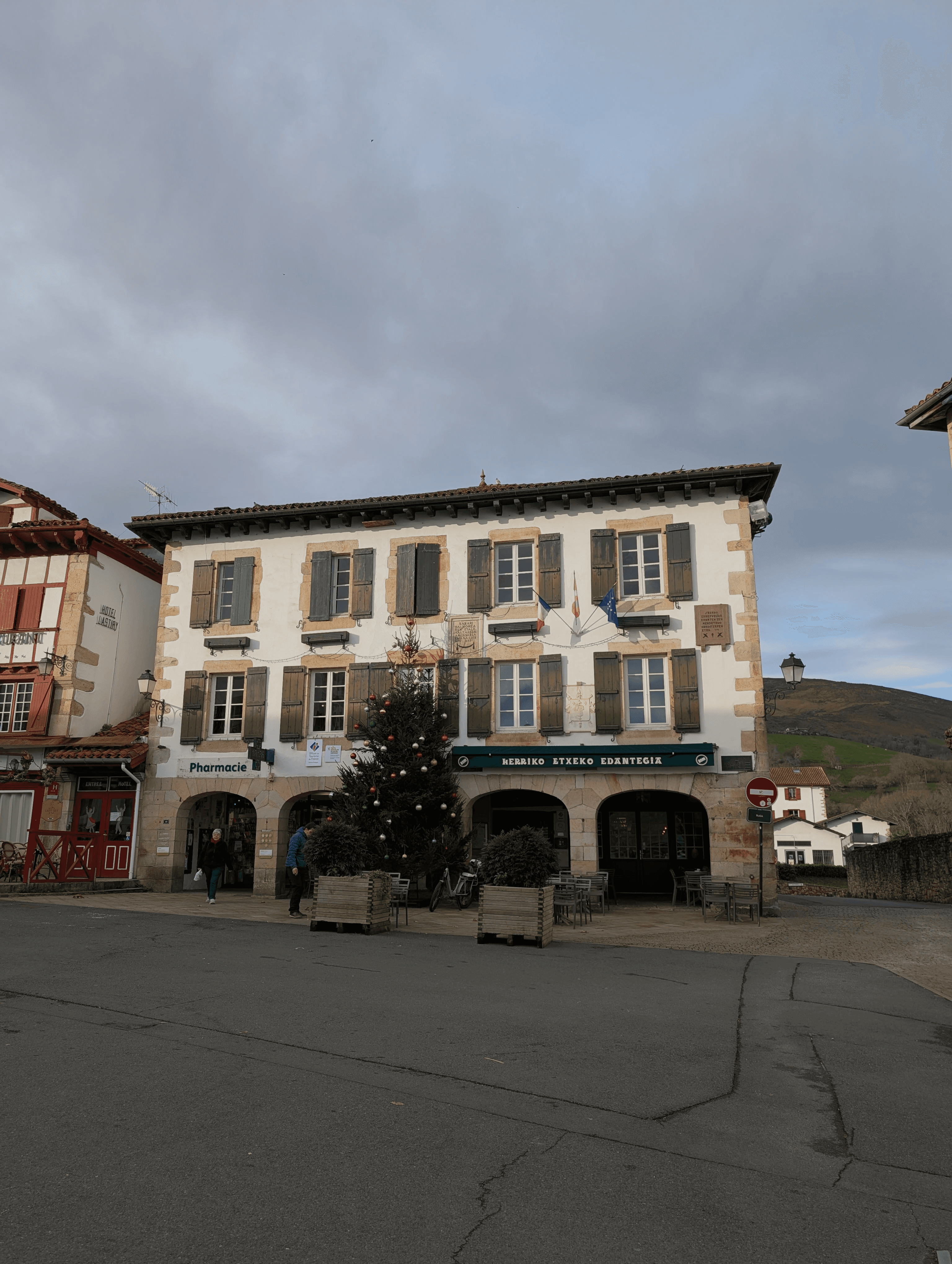 Traditional Basque house in a village square, with green wooden shutters and Christmas tree, illustrating a private family journey through the Basque Country.
