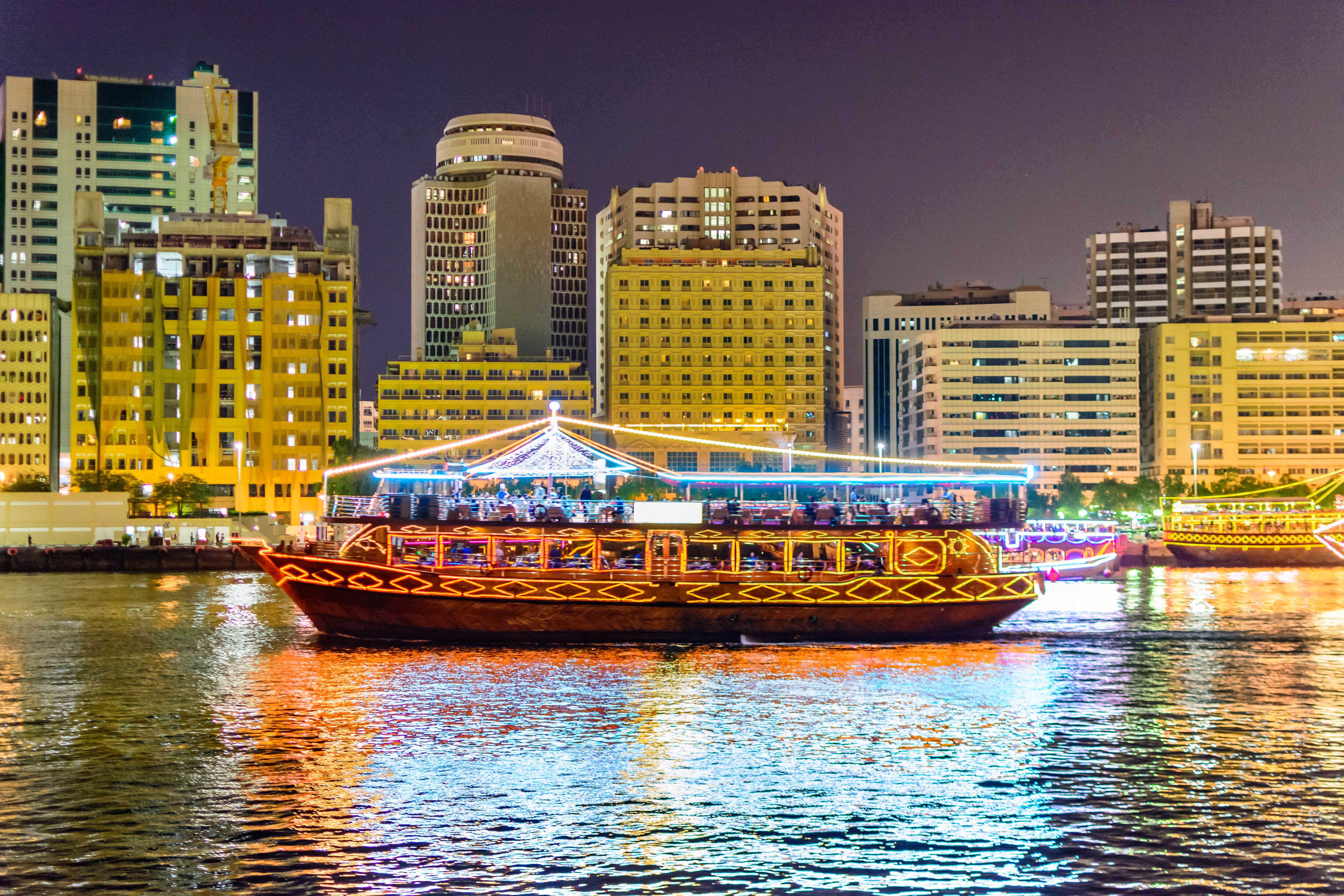 Dhow cruise on Dubai Creek with city skyline at night.