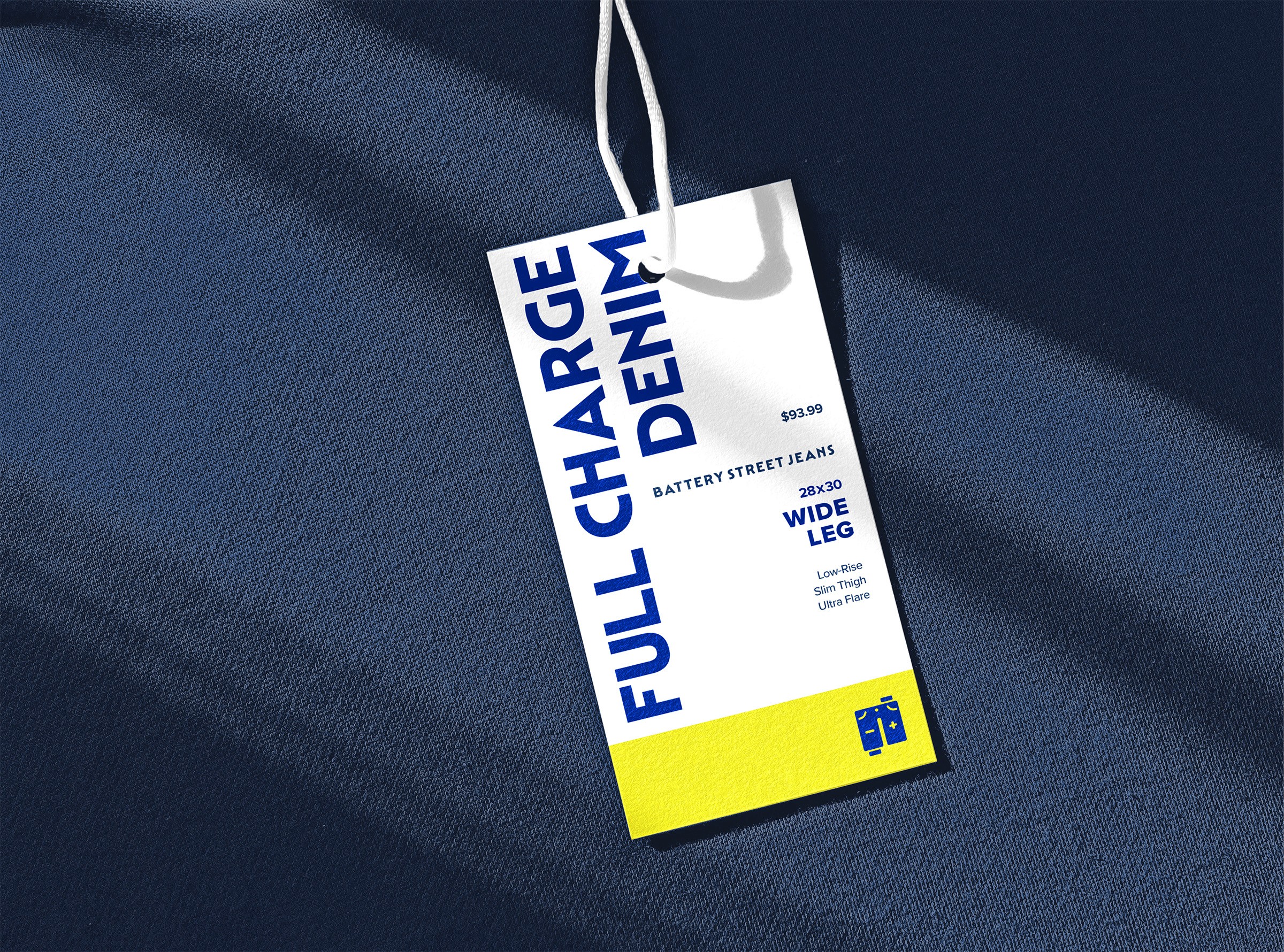 A white clothing tag attached to a blue fabric background features bold blue text reading "FULL CHARGE DENIM" with pricing and style information, emphasizing wide-leg jeans and a modern, minimalist design.
