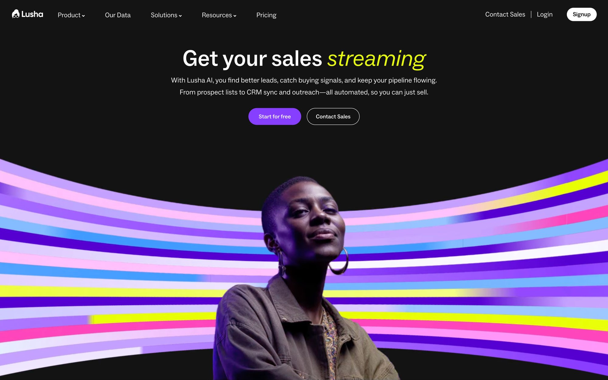 Lusha homepage with a smiling woman against vibrant stripes, featuring 'Get your sales streaming' headline and buttons.