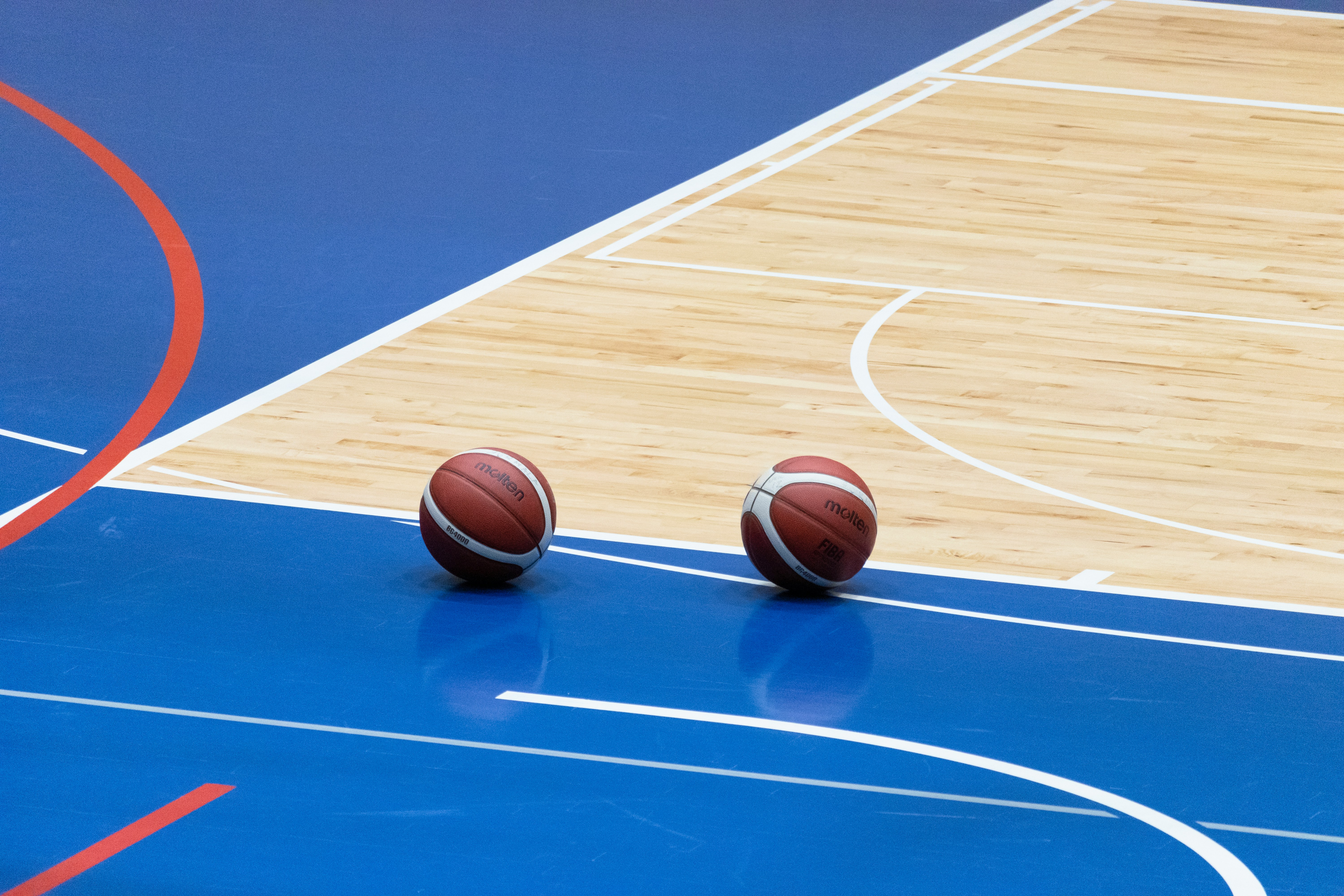 Two basketballs on a blue court