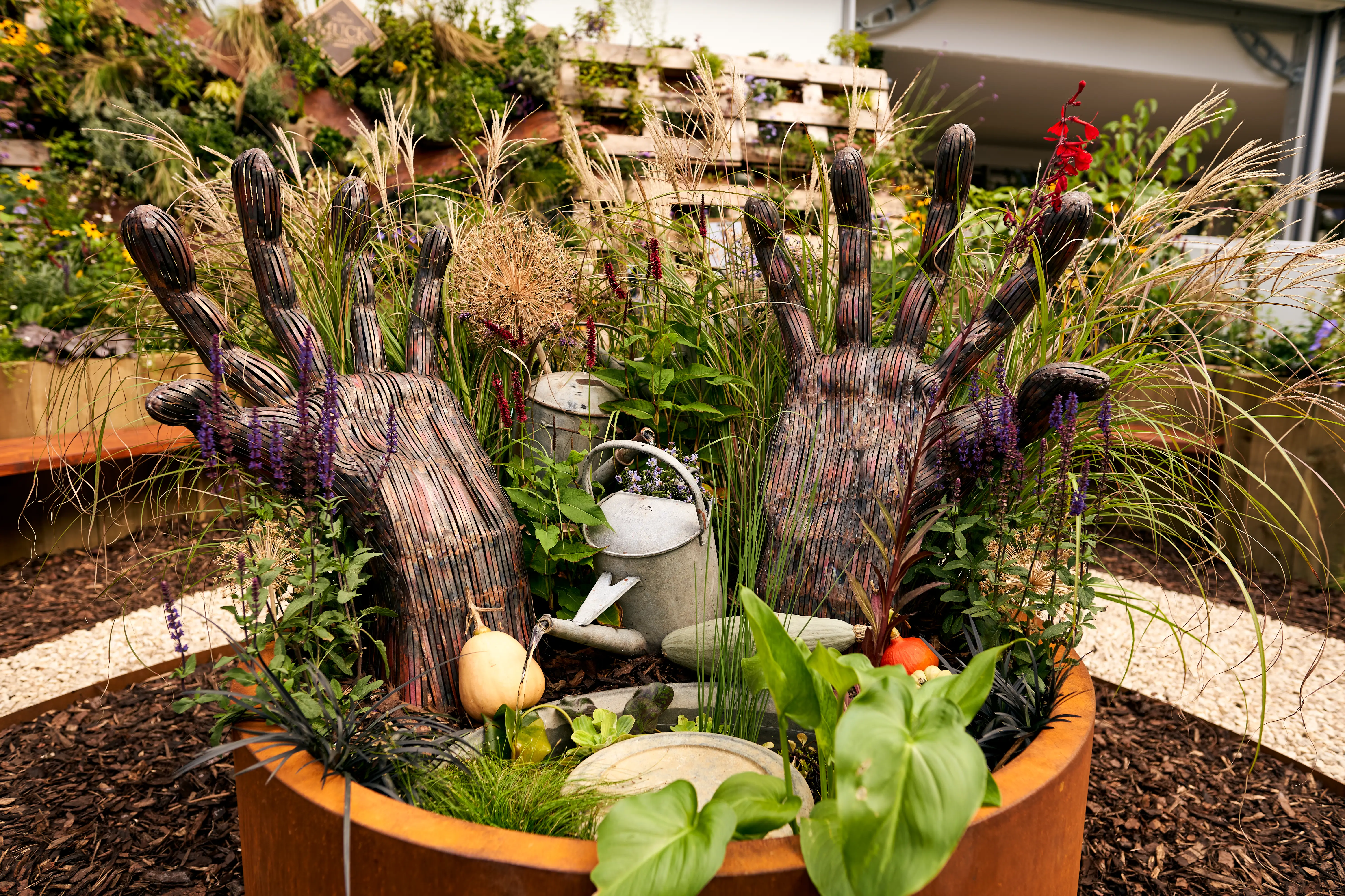 A circular garden bed filled with various plants, including herbs and vegetables, surrounded by decorative elements.