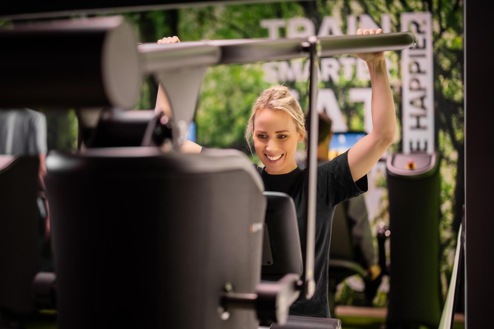 A person works out on a weight machine indoors, on a green background.