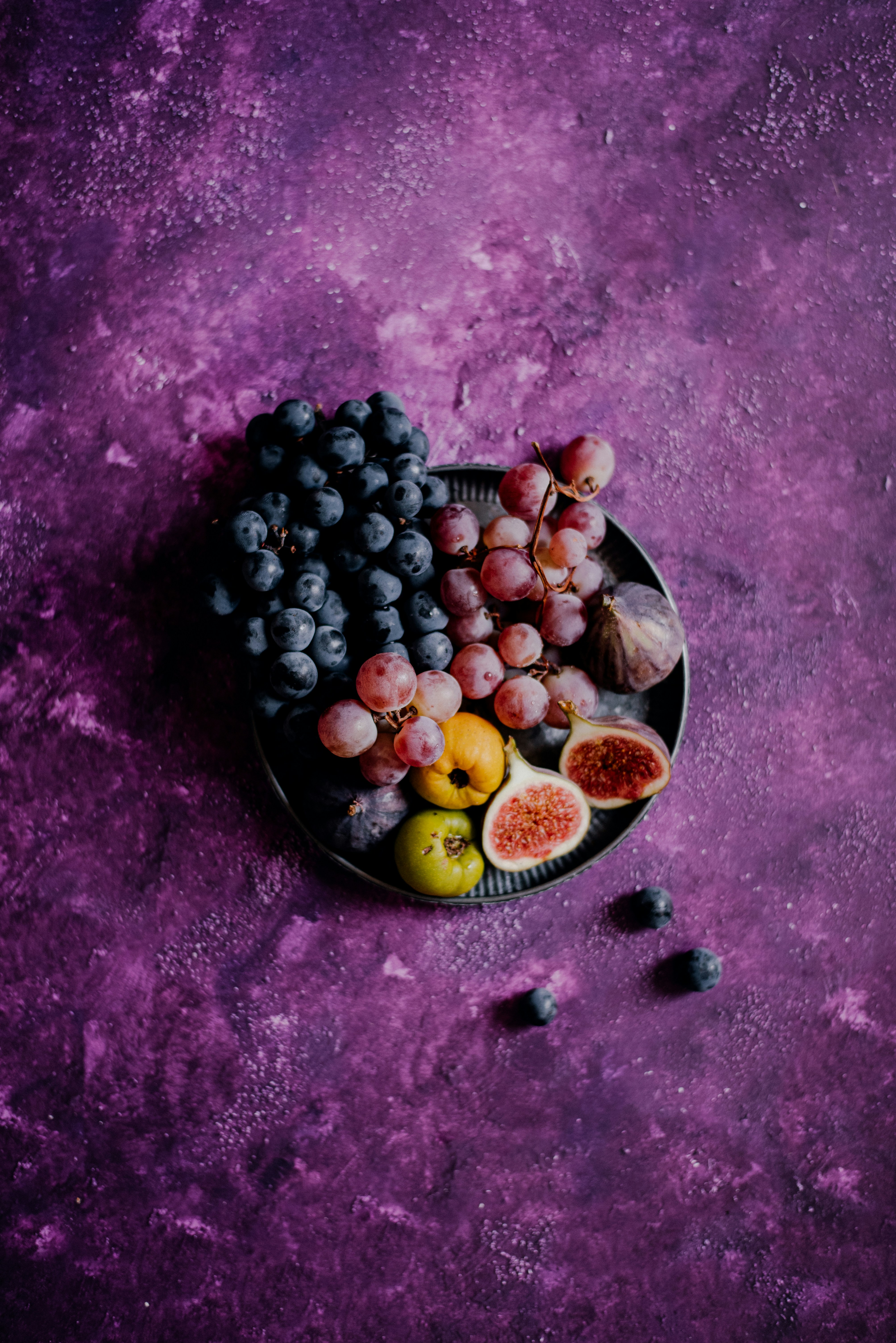 A plate of fruit on a purple background