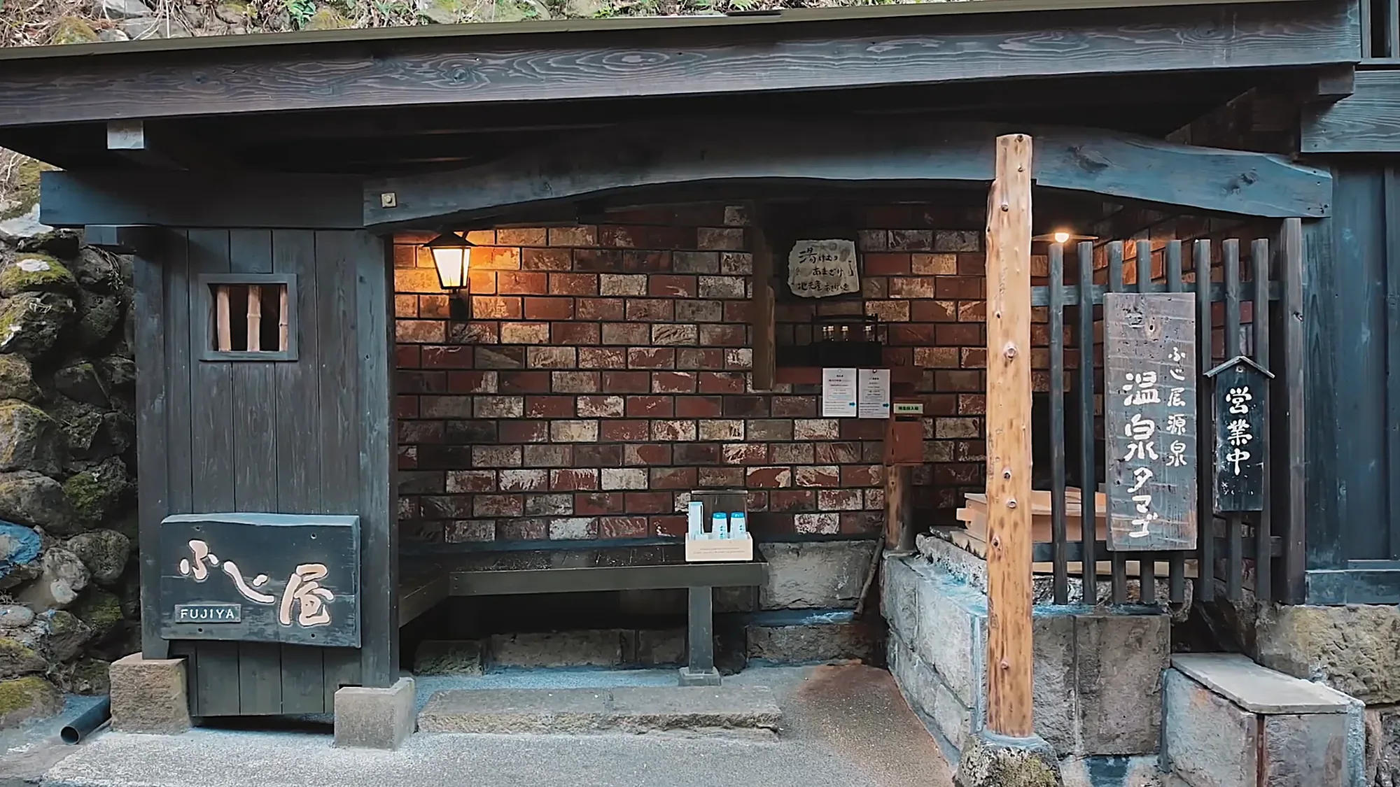 An inn entrance at Kurokawa Onsen faced with a wall of wooden tegata plaques, under a yumeguri bath-hopping sign