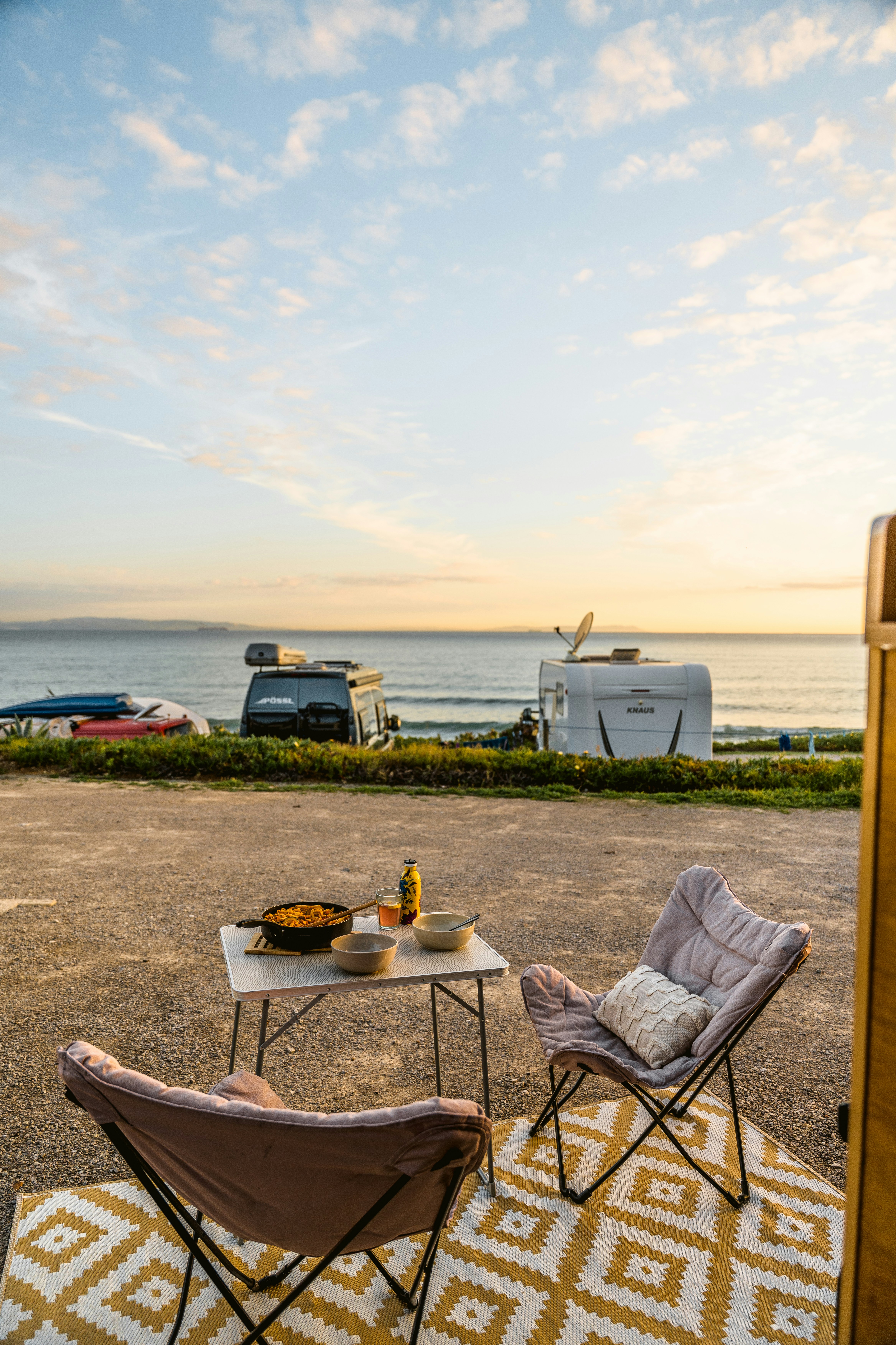 Campervans parked by the ocean with outdoor seating