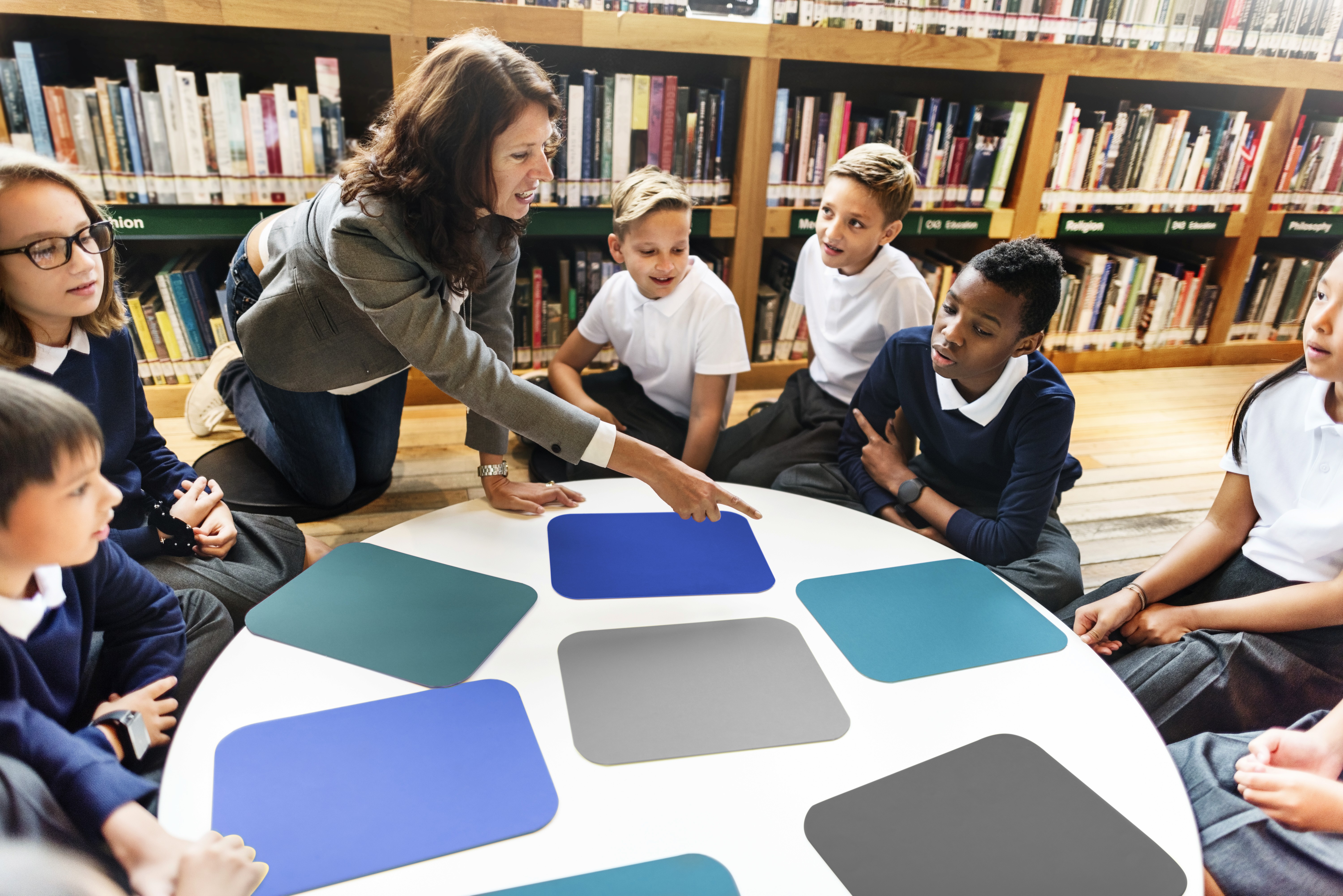 Eine Lehrerin sitzt im Kreis mit ihren Schüler:innen.