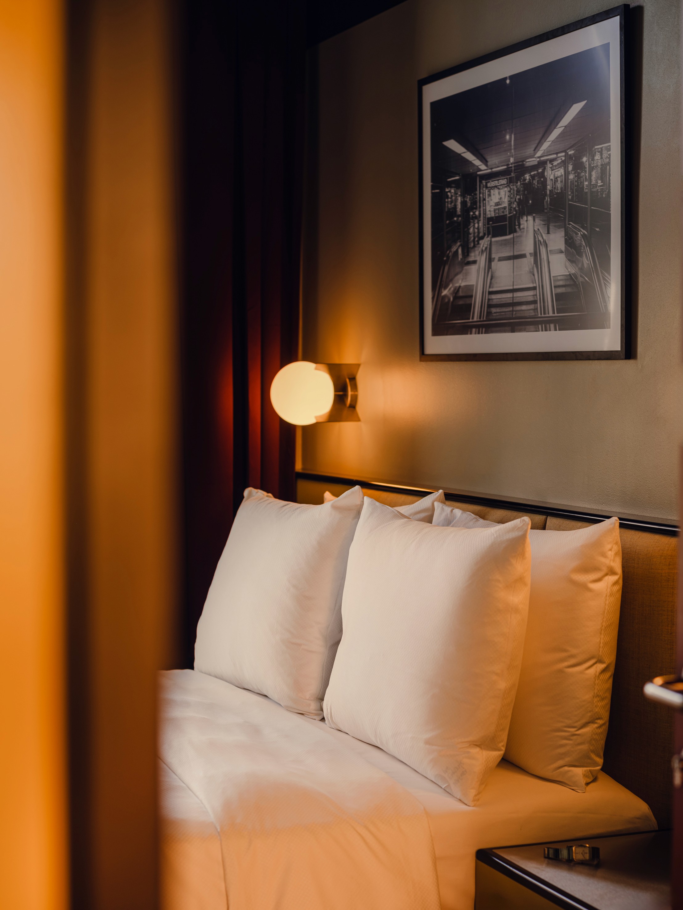 View of bed with cleanly organized pillows in The Companion Hotel