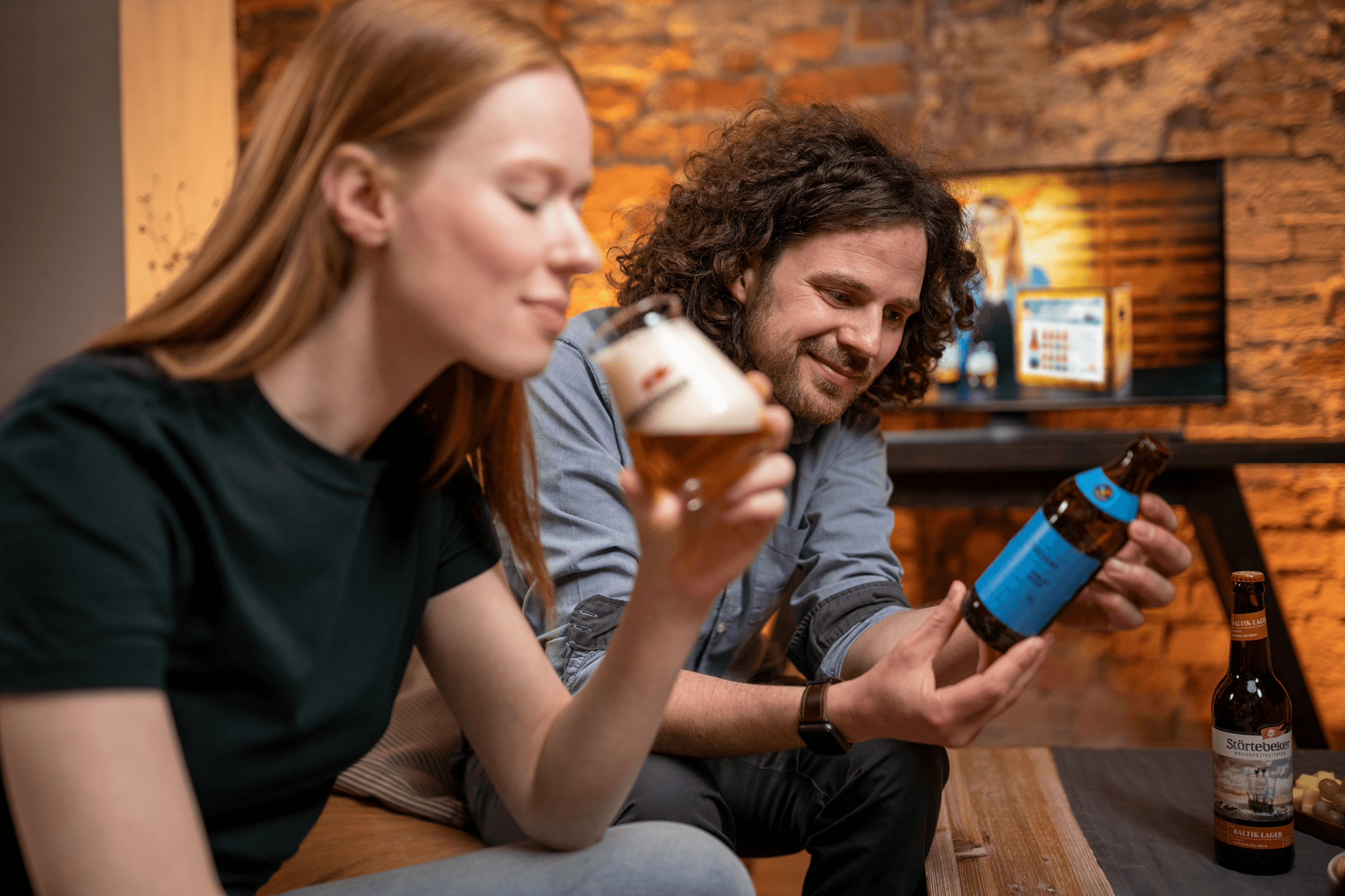 Man and woman with beer bottles and glass.